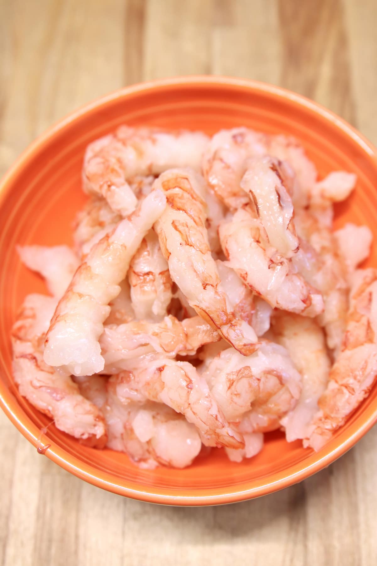 peeled jumbo shrimp in an orange bowl.