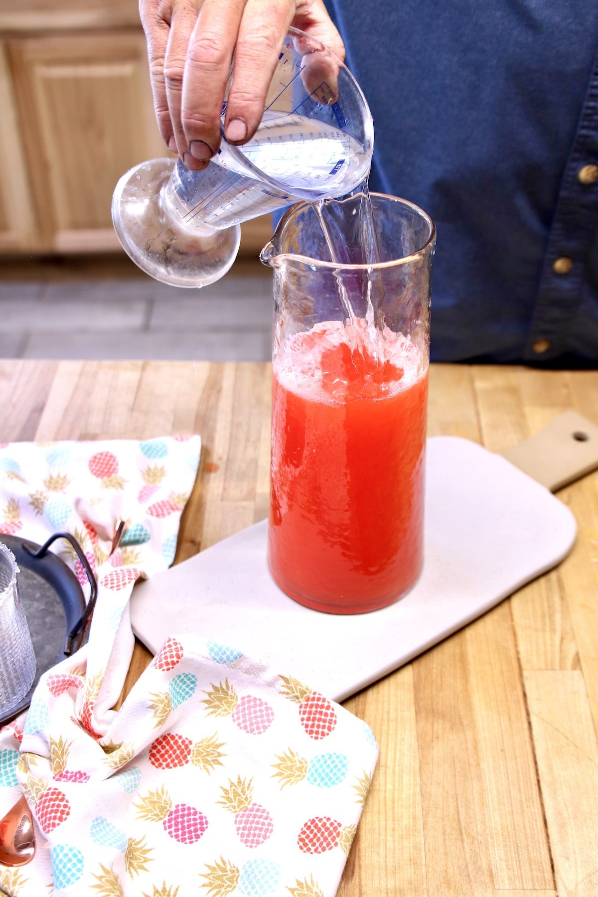 Pouring tequila into pitcher of punch.