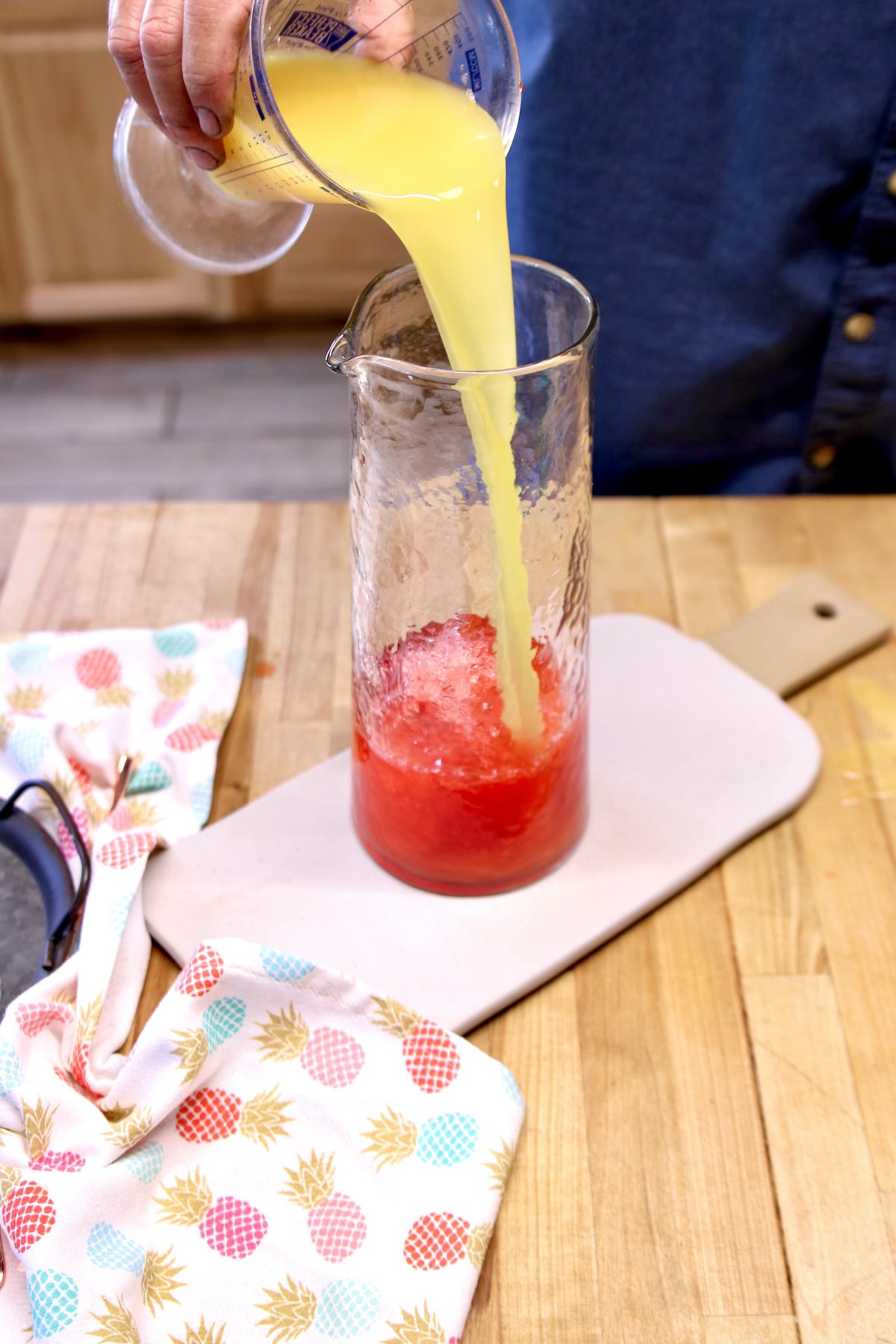 Pouring pineapple juice into a pitcher.