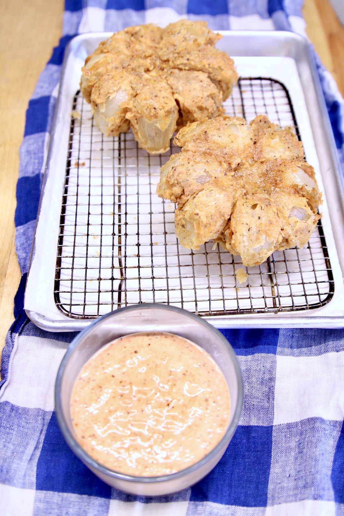 Blooming onions draining on a wire rack.
