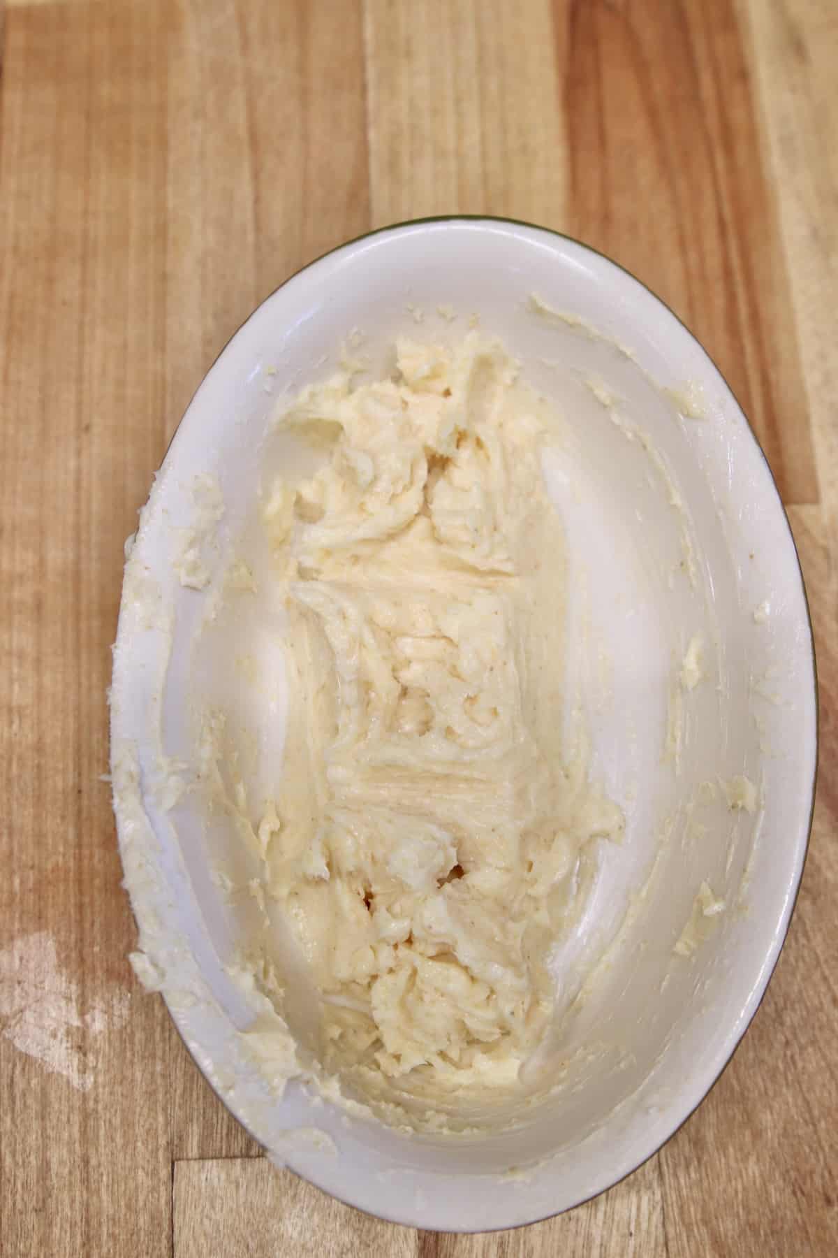 Oval bowl of softened garlic butter.