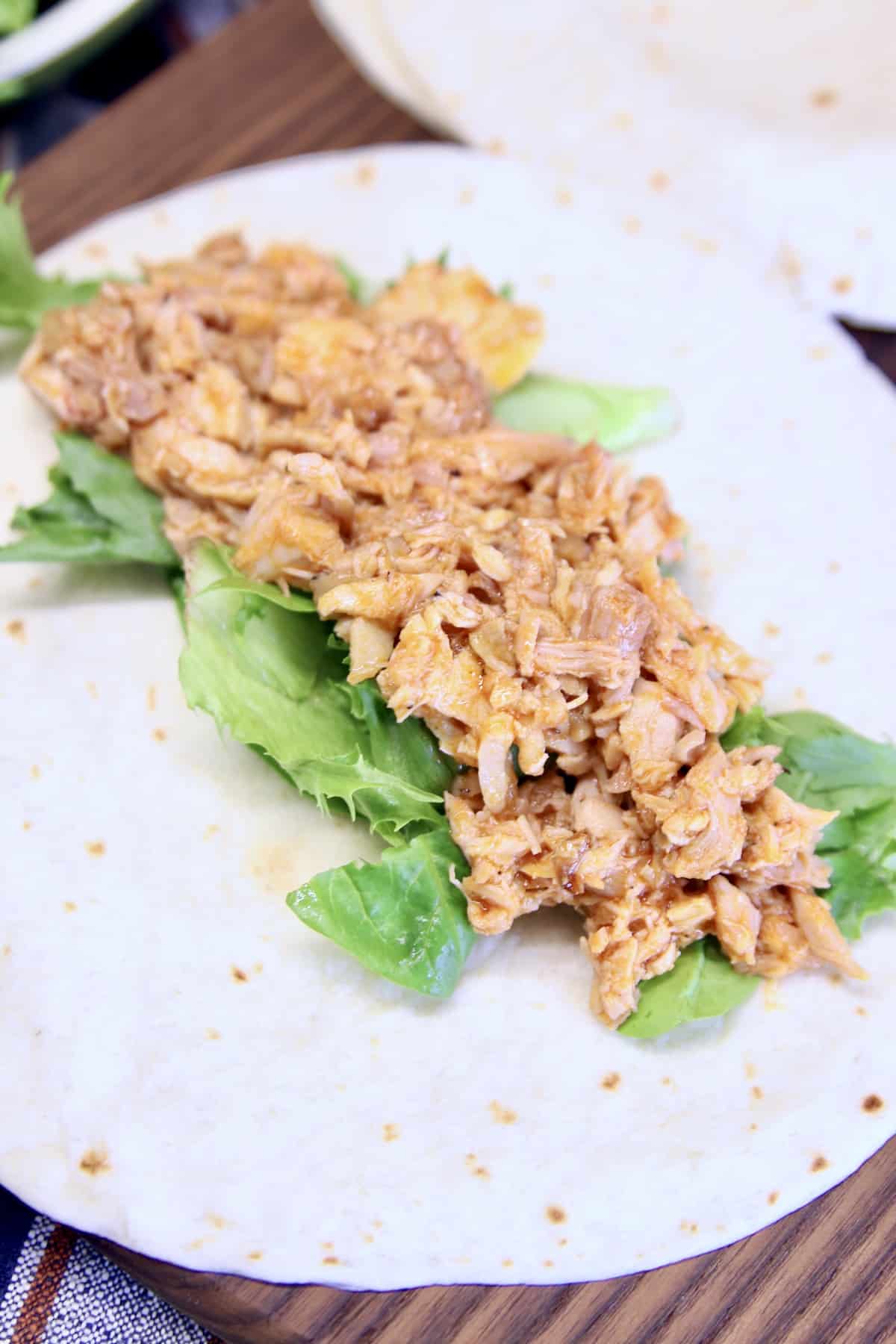 Flour tortilla with lettuce and shredded chicken.