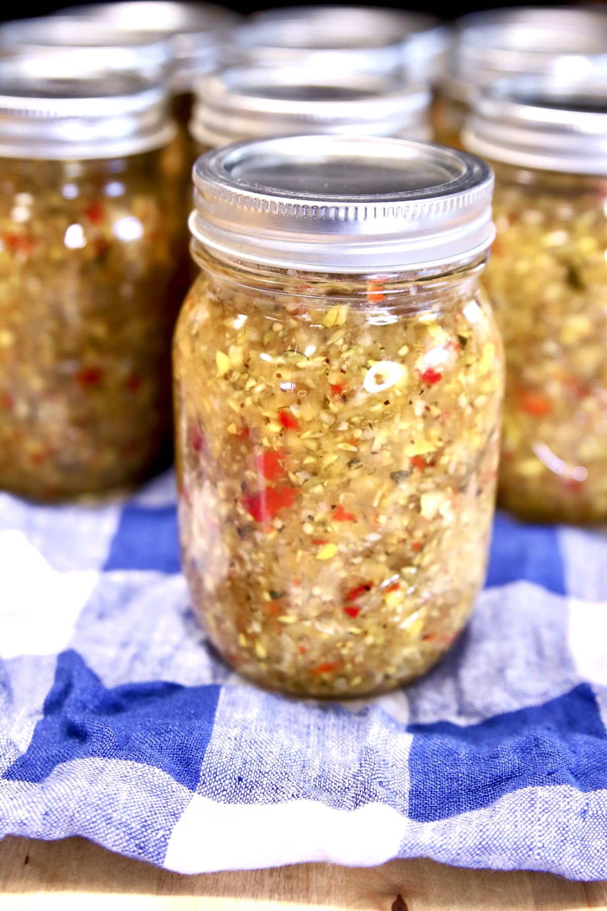 Jars of squash relish on a blue check towel.