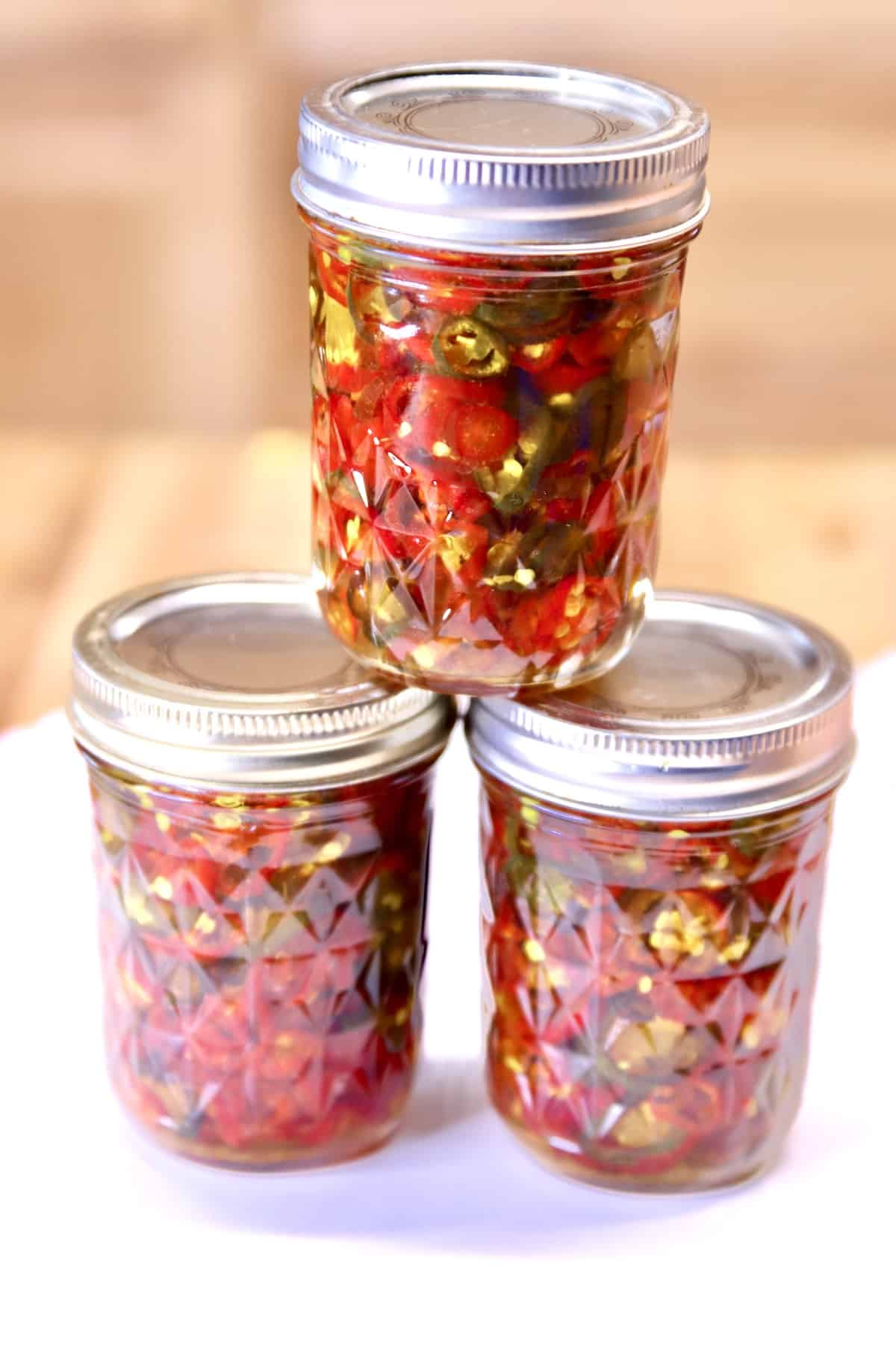 3 jars candied jalapenos stacked.