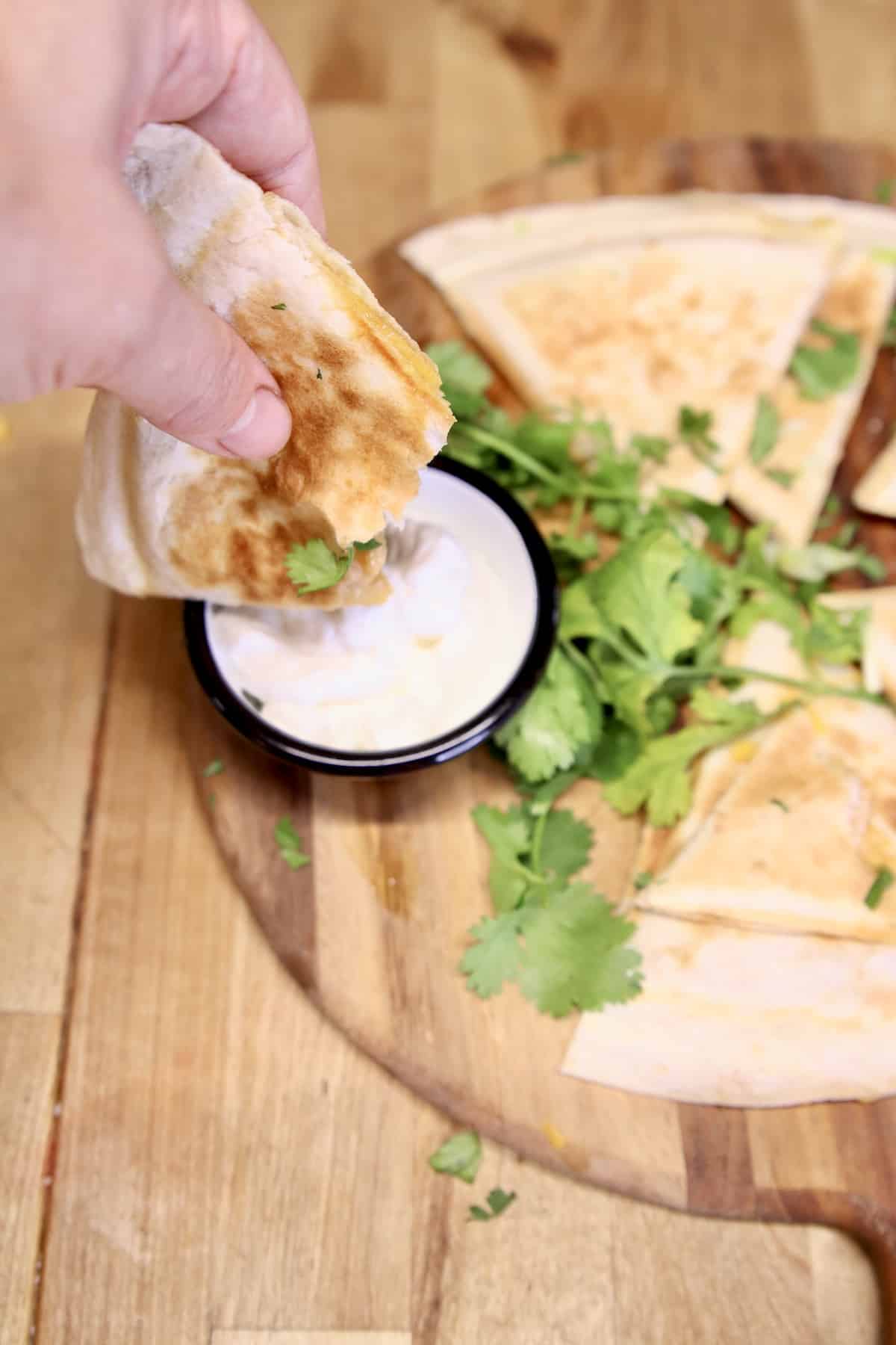 Dipping quesadilla into sour cream bowl.