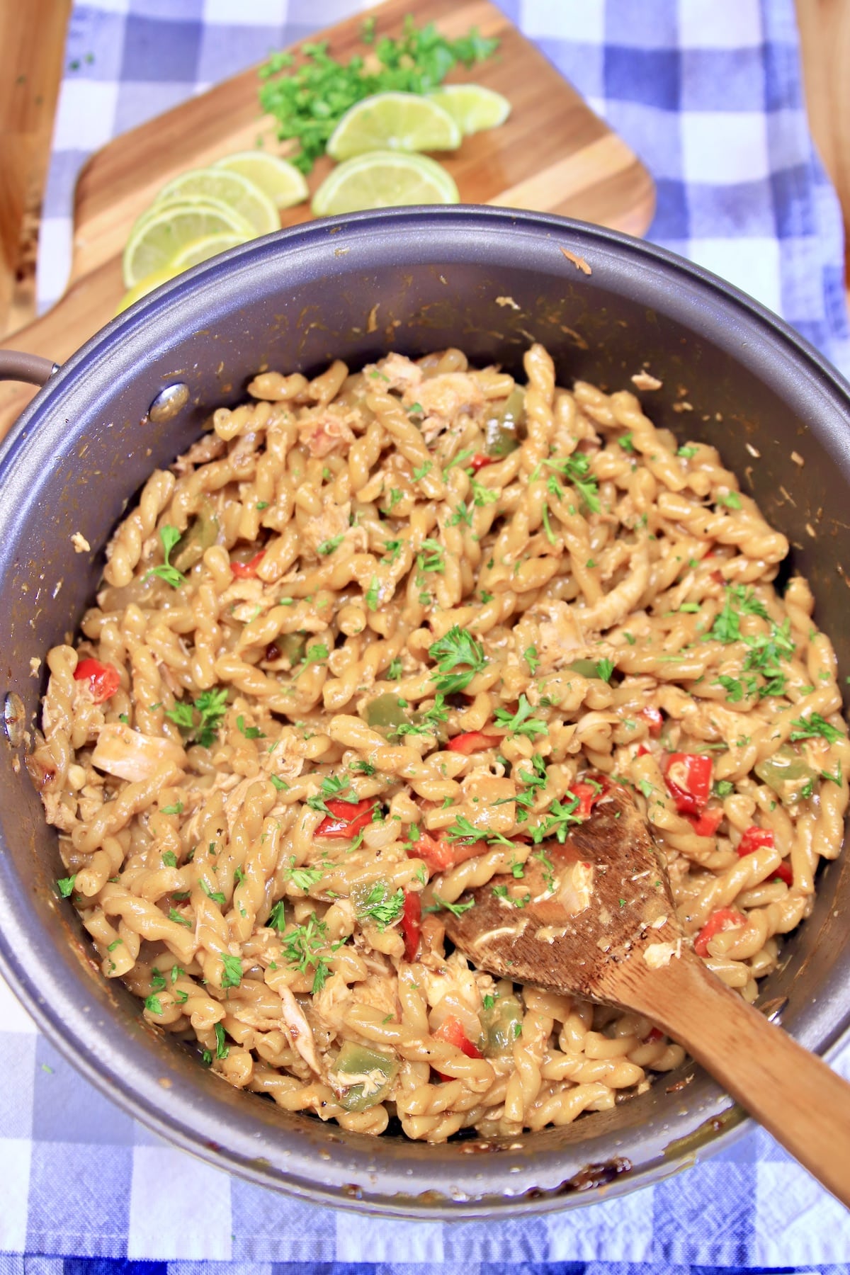 Pan with chicken fajita pasta, wooden spoon.