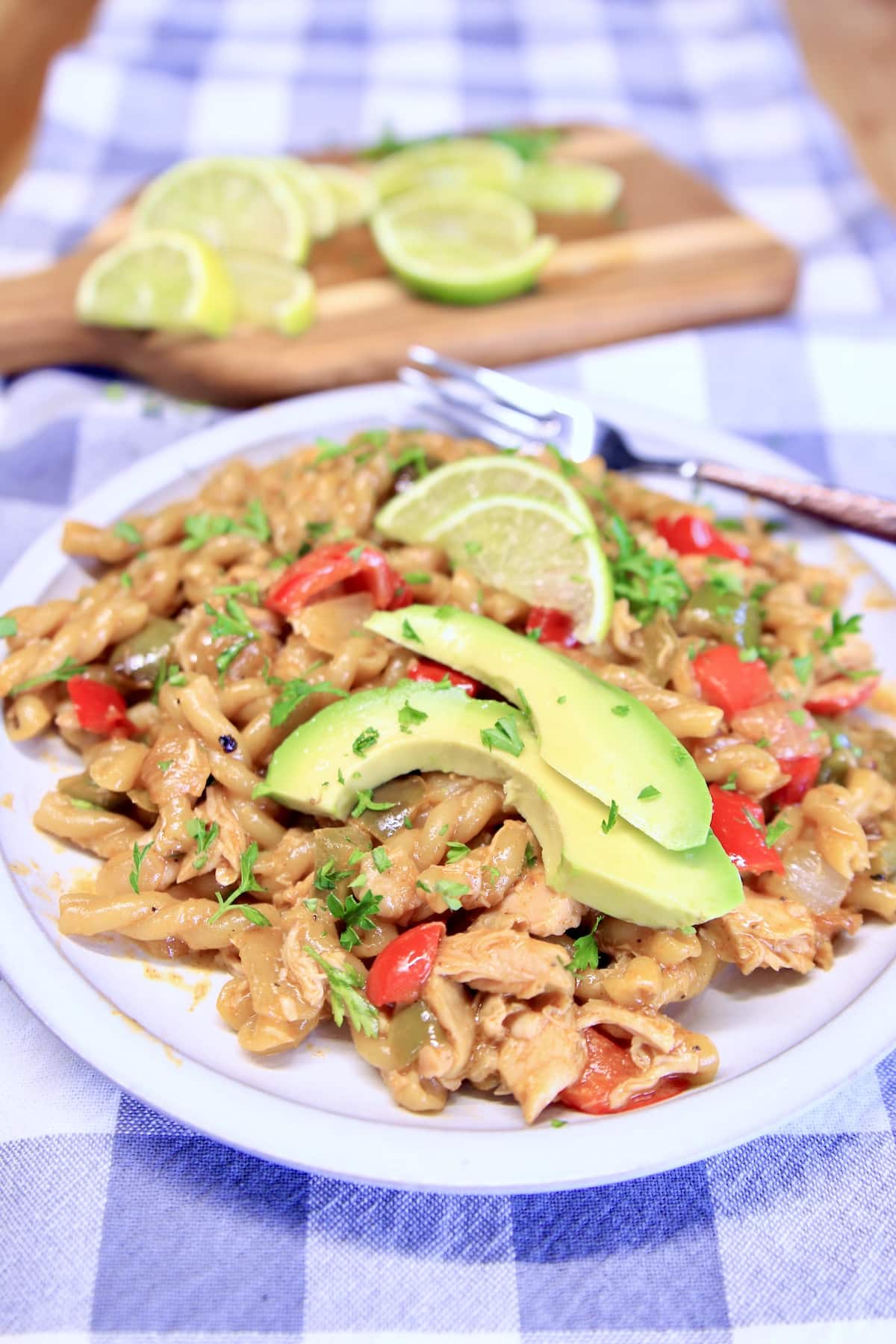 Plated chicken fajita pasta with avocado slices.