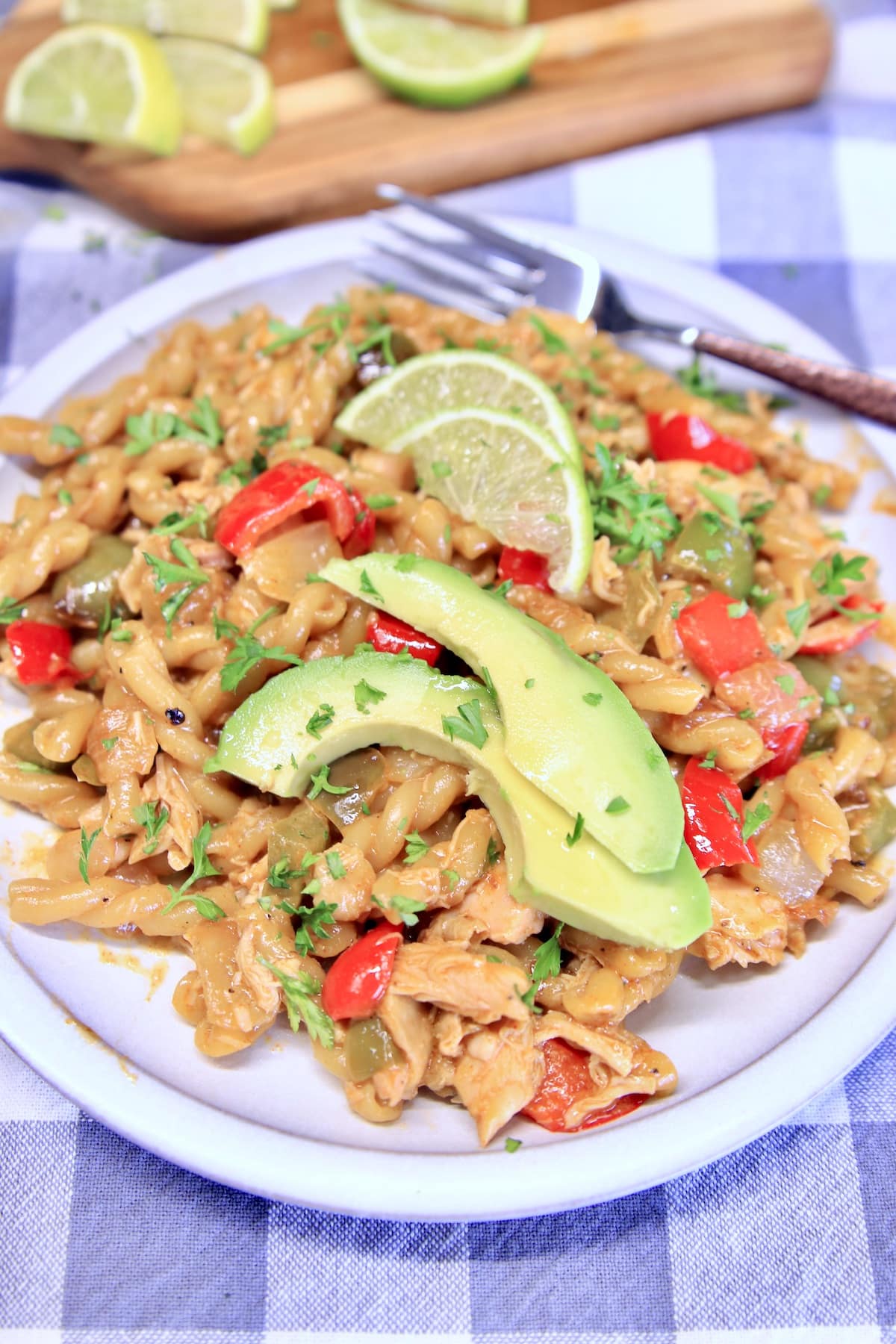 Chicken fajita pasta with avocado and lime slices.