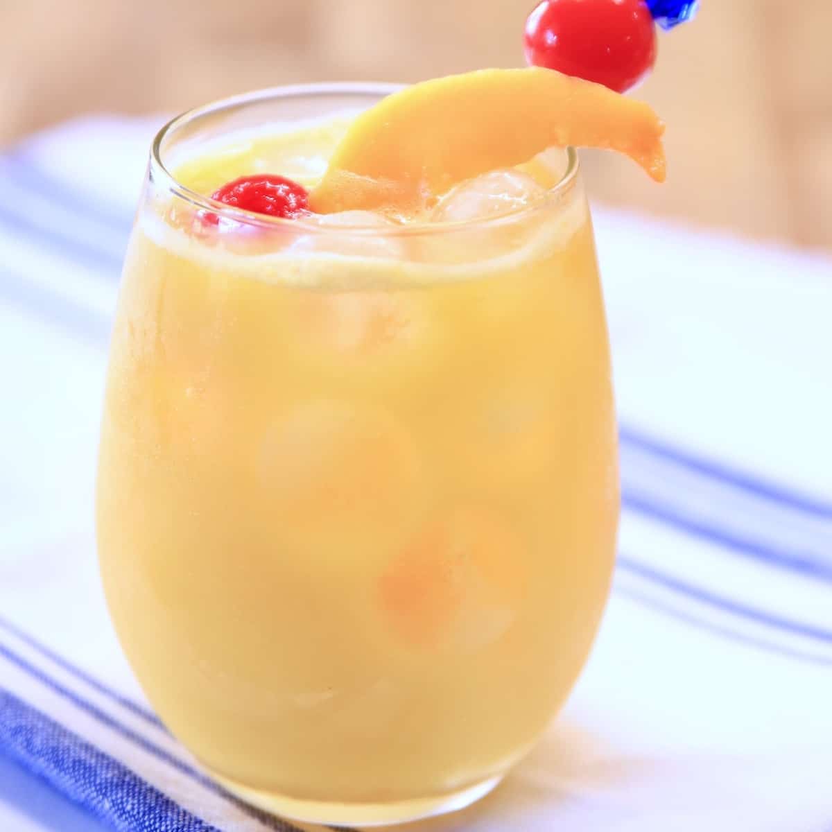 Stemless wine glass with mango screwdriver cocktail. Cherry & mango garnish.