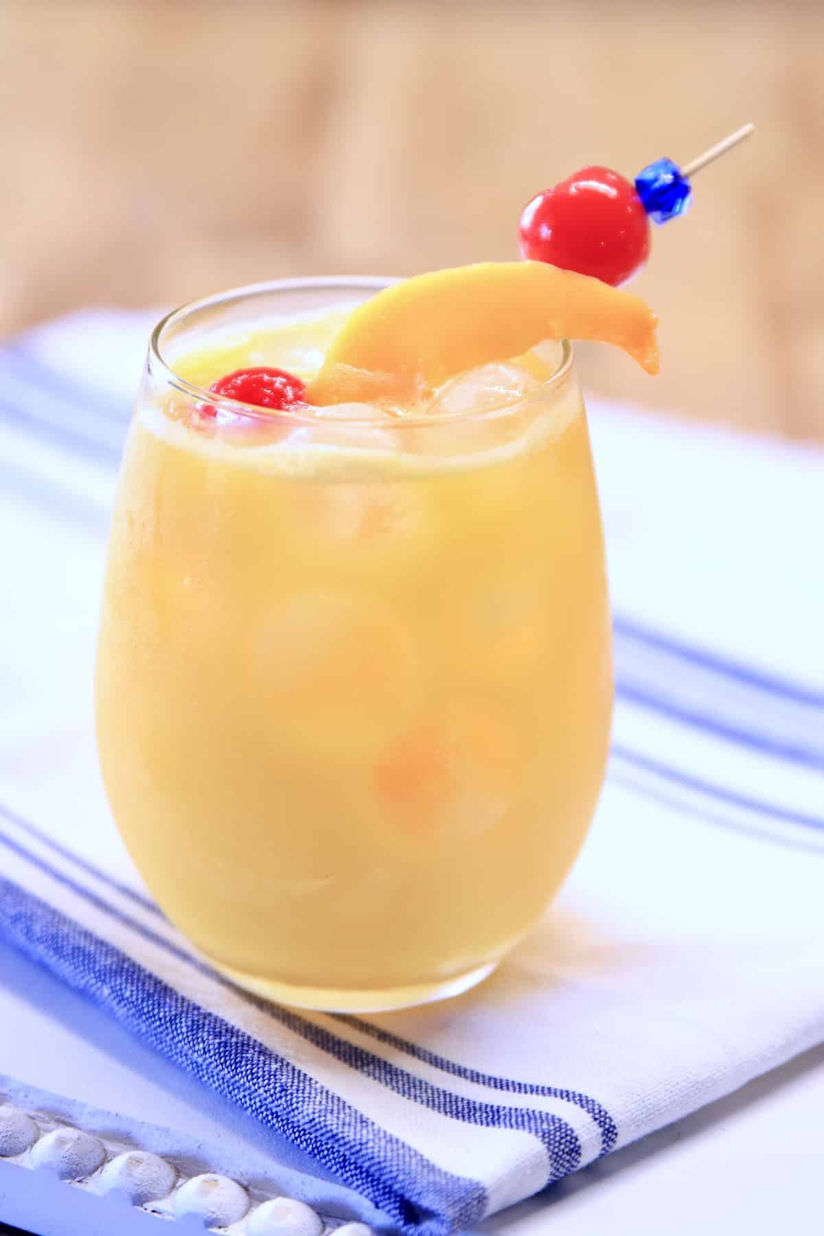 Mango cocktail in a stemless wine glass on a white towel.