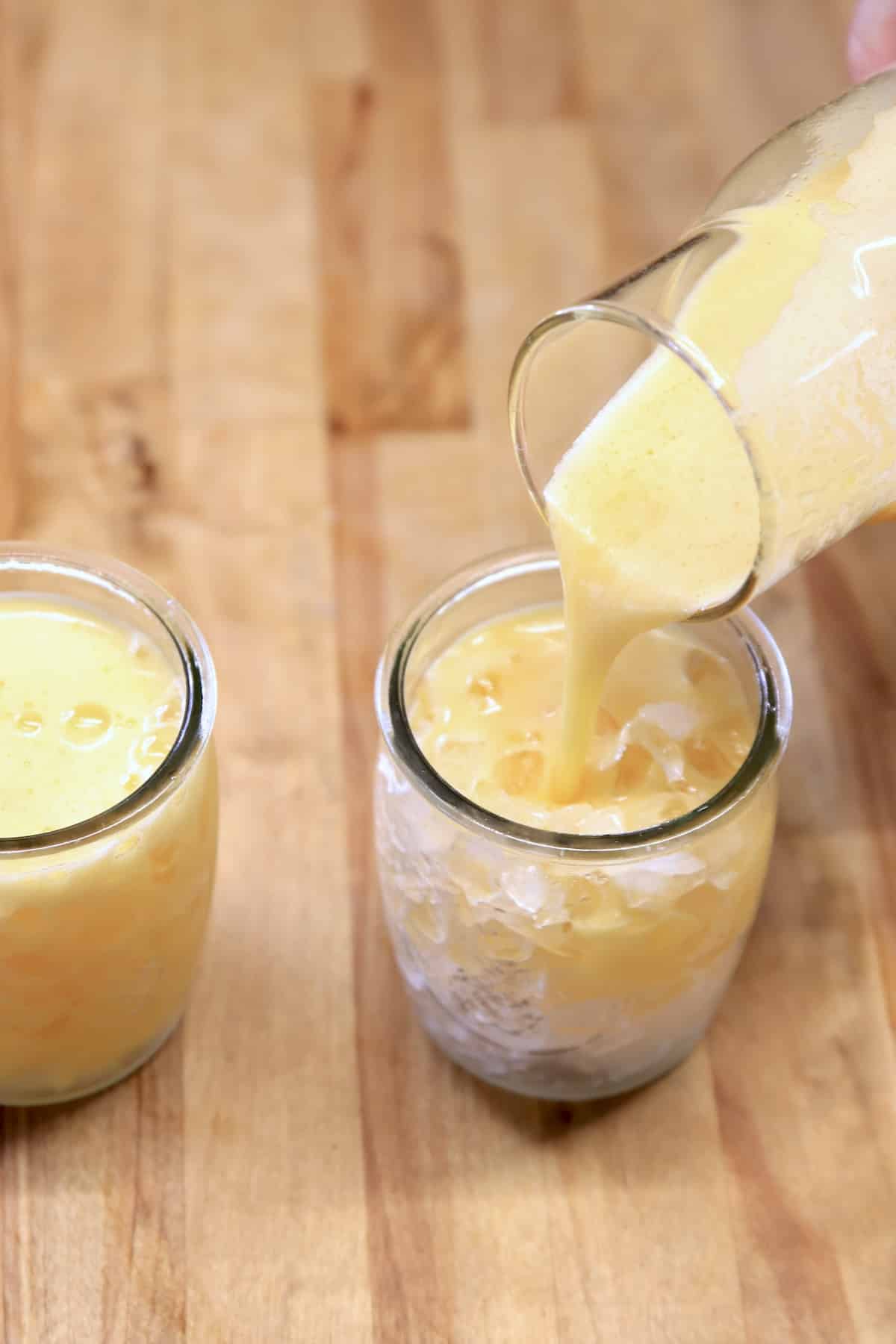 Filling glasses with pineapple mango cocktail.