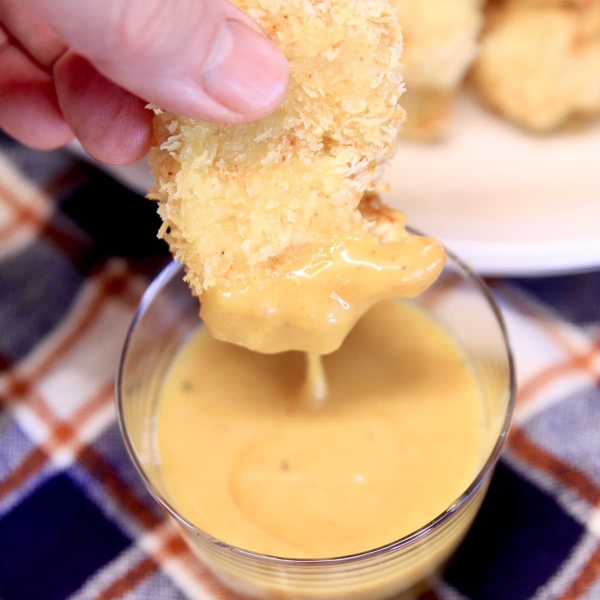 Chicken nugget dipping into yellow sauce.