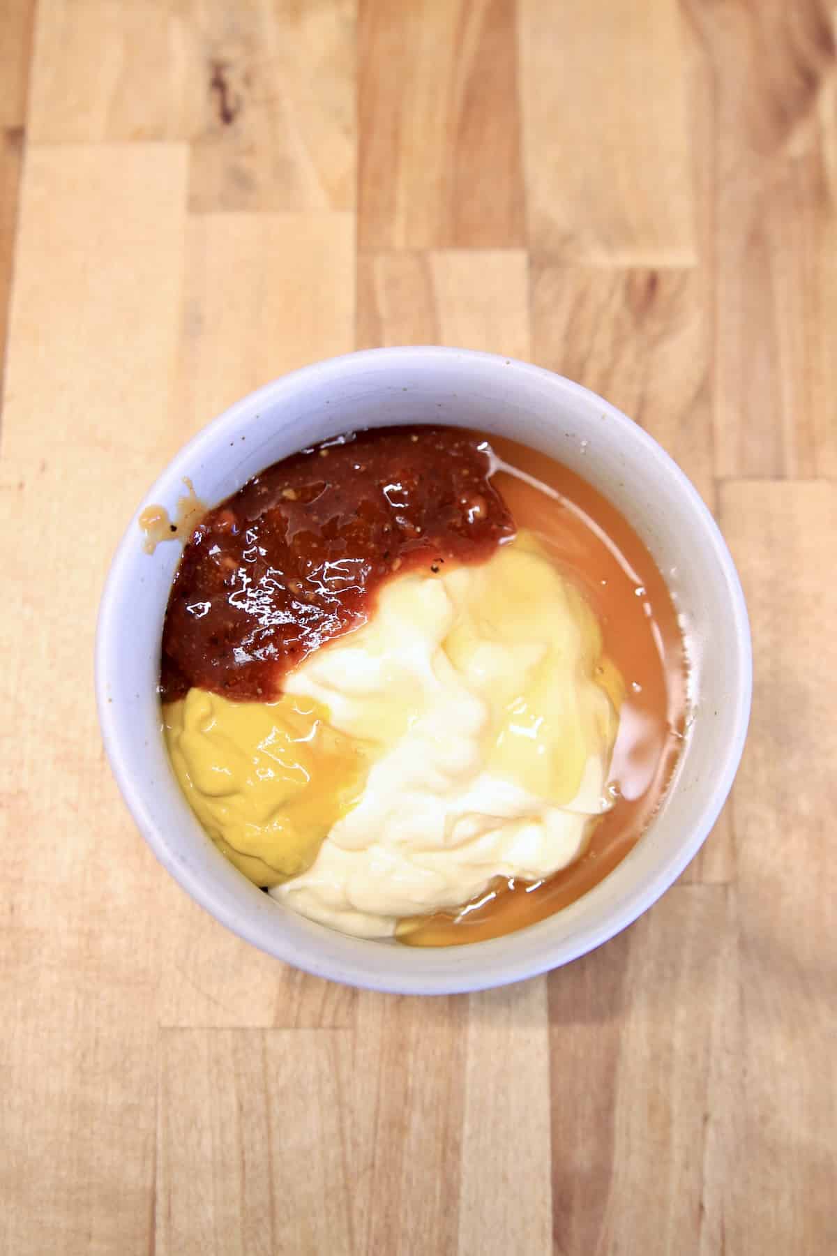 Bowl with mayo, mustard, bbq sauce and honey.