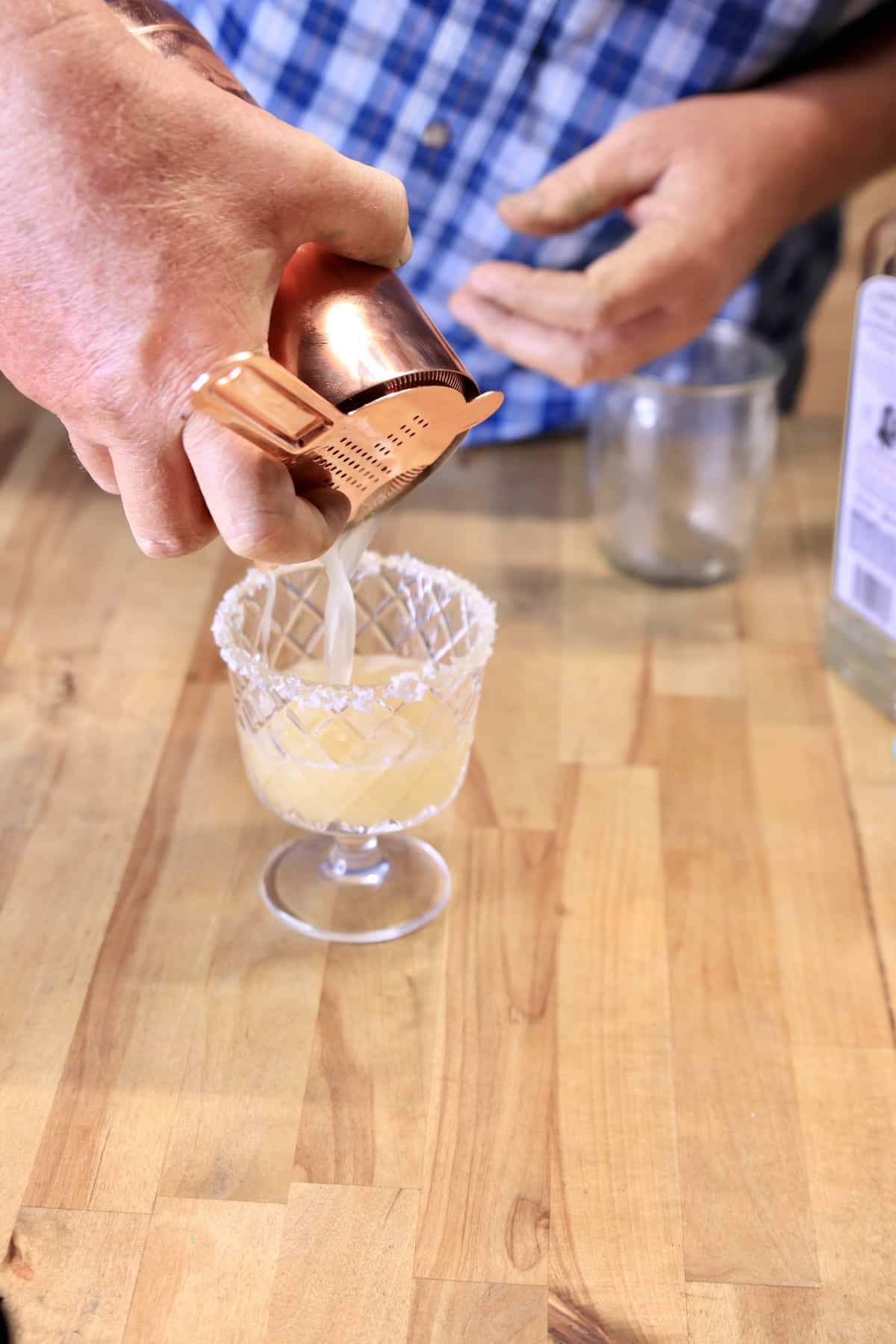 Straining margarita into glass.