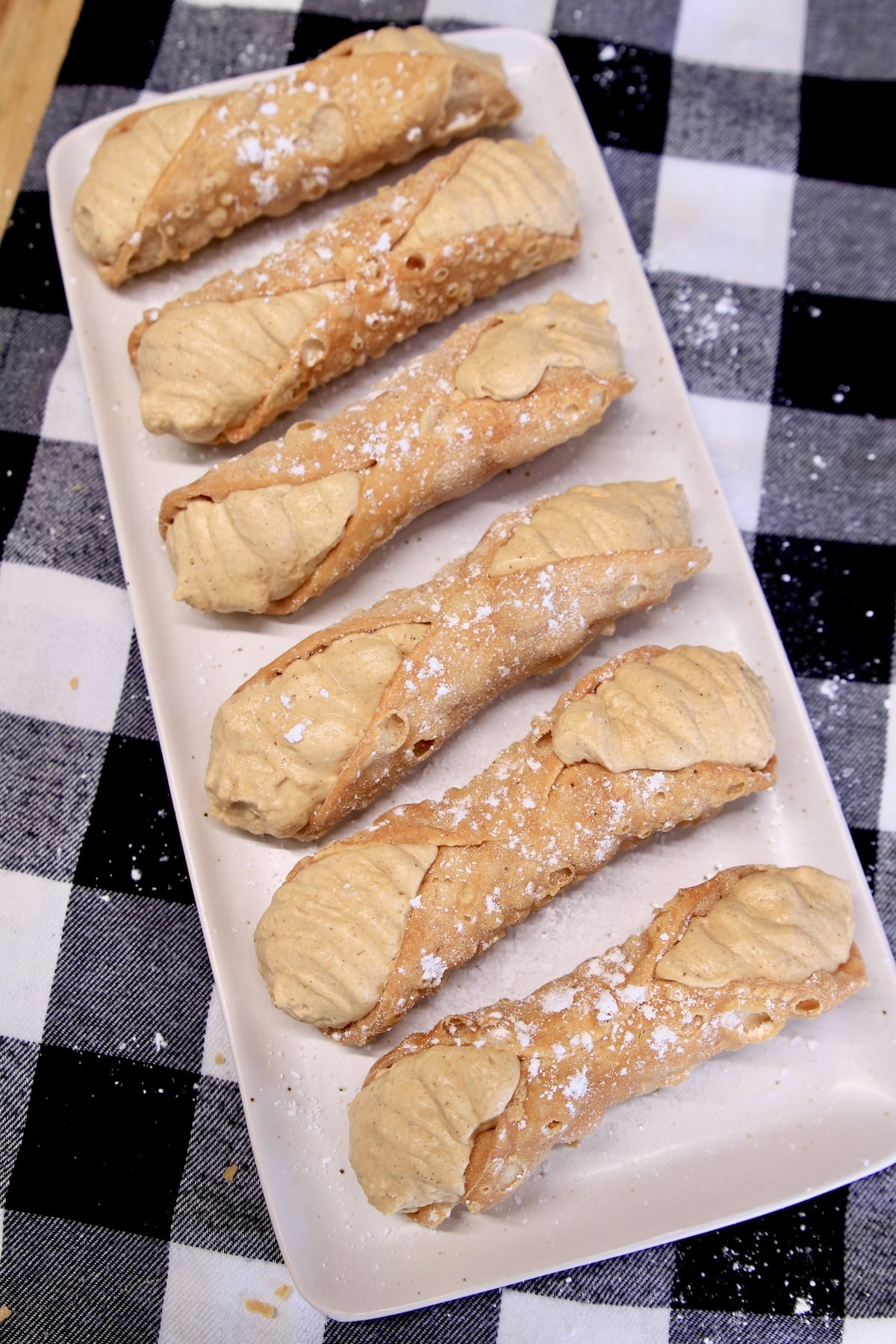 Platter of 6 pumpkin cannoli with powdered sugar garnish.