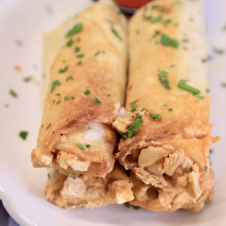 Rolled Chicken Tacos cut in half on a plate.
