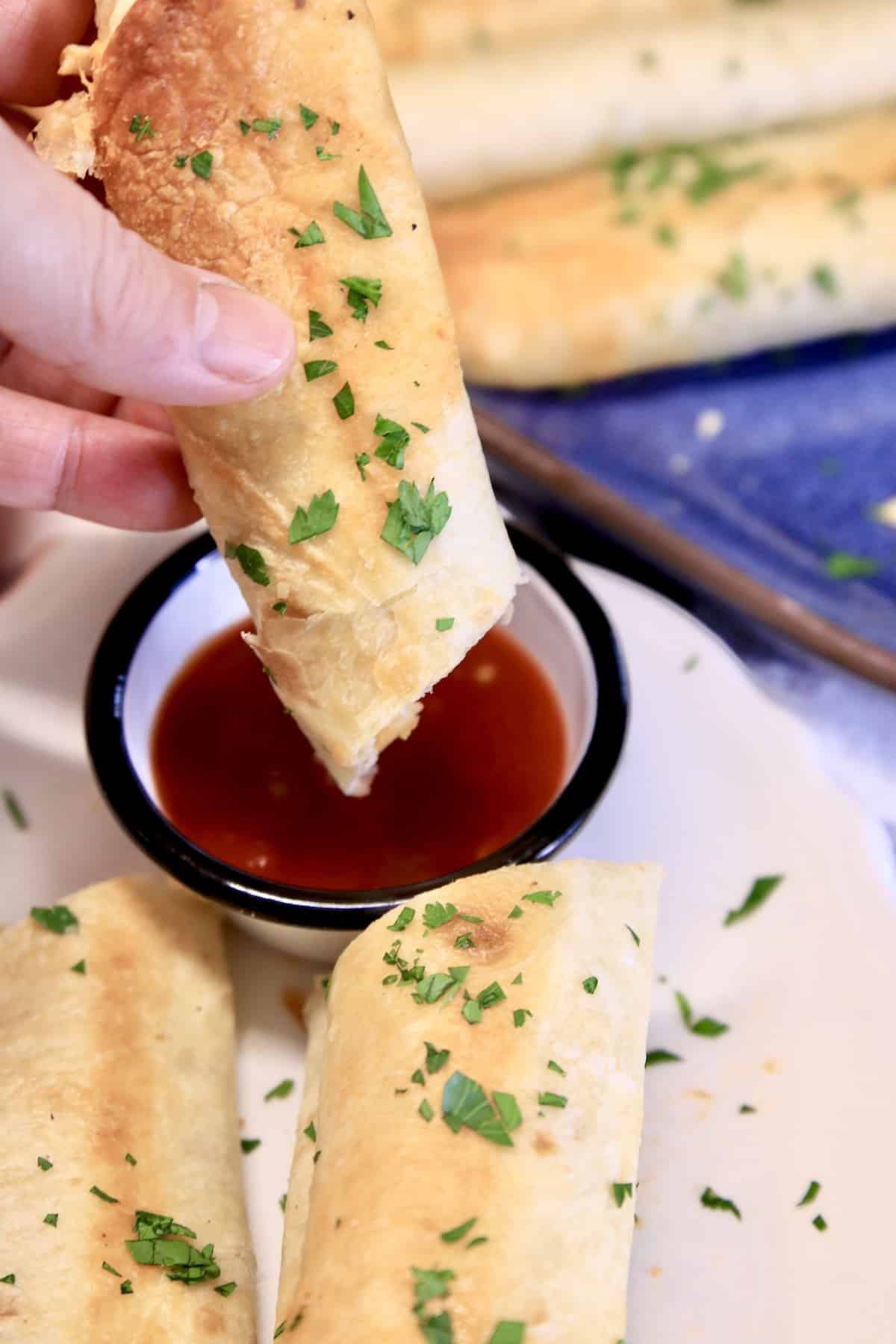 Dipping rolled taco in picante sauce.
