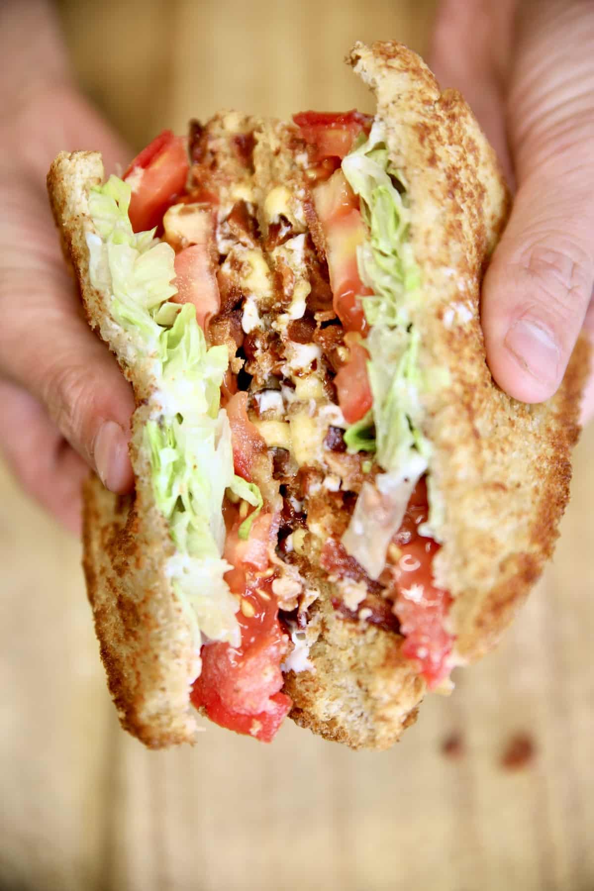 Bacon Grilled Cheese Sandwich, cut in half, held in hands.