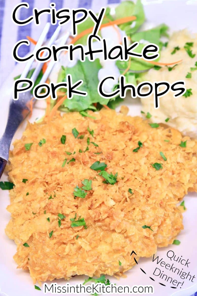 Cornflake pork chop on a plate with potatoes and salad.