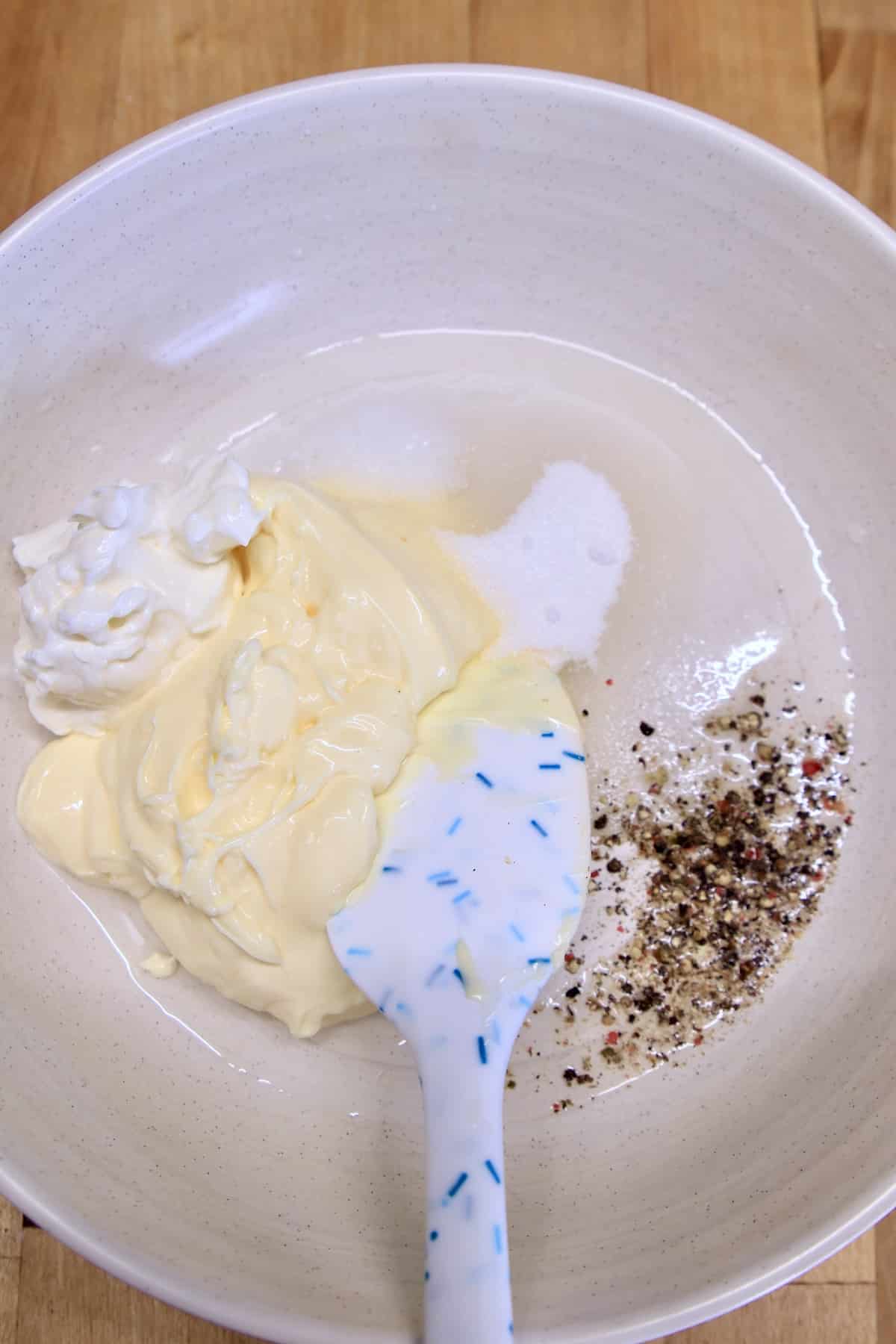 Bowl with slaw dressing ingredients with spatula.