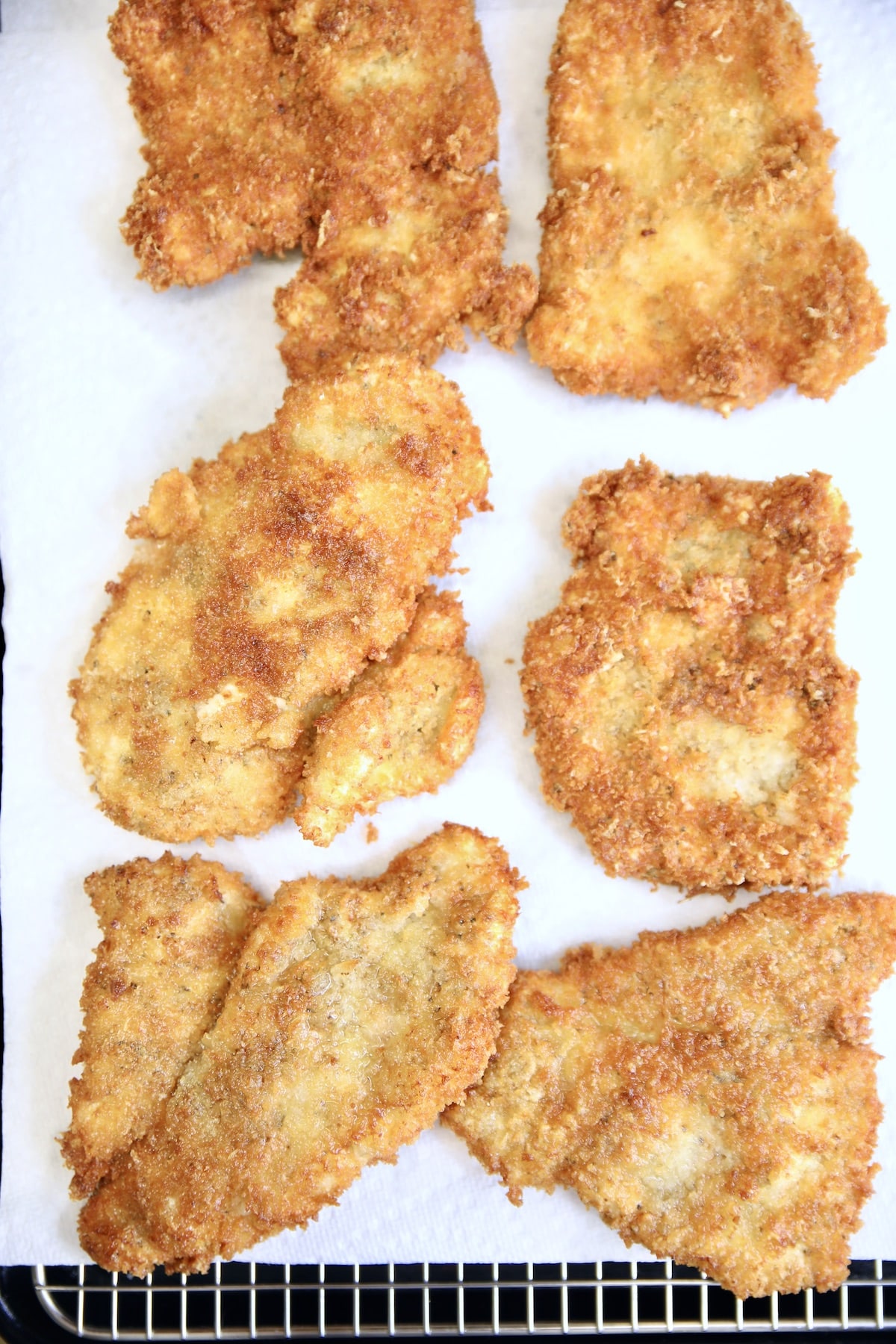 Fried chicken parmesan on a paper towel lined wire rack.