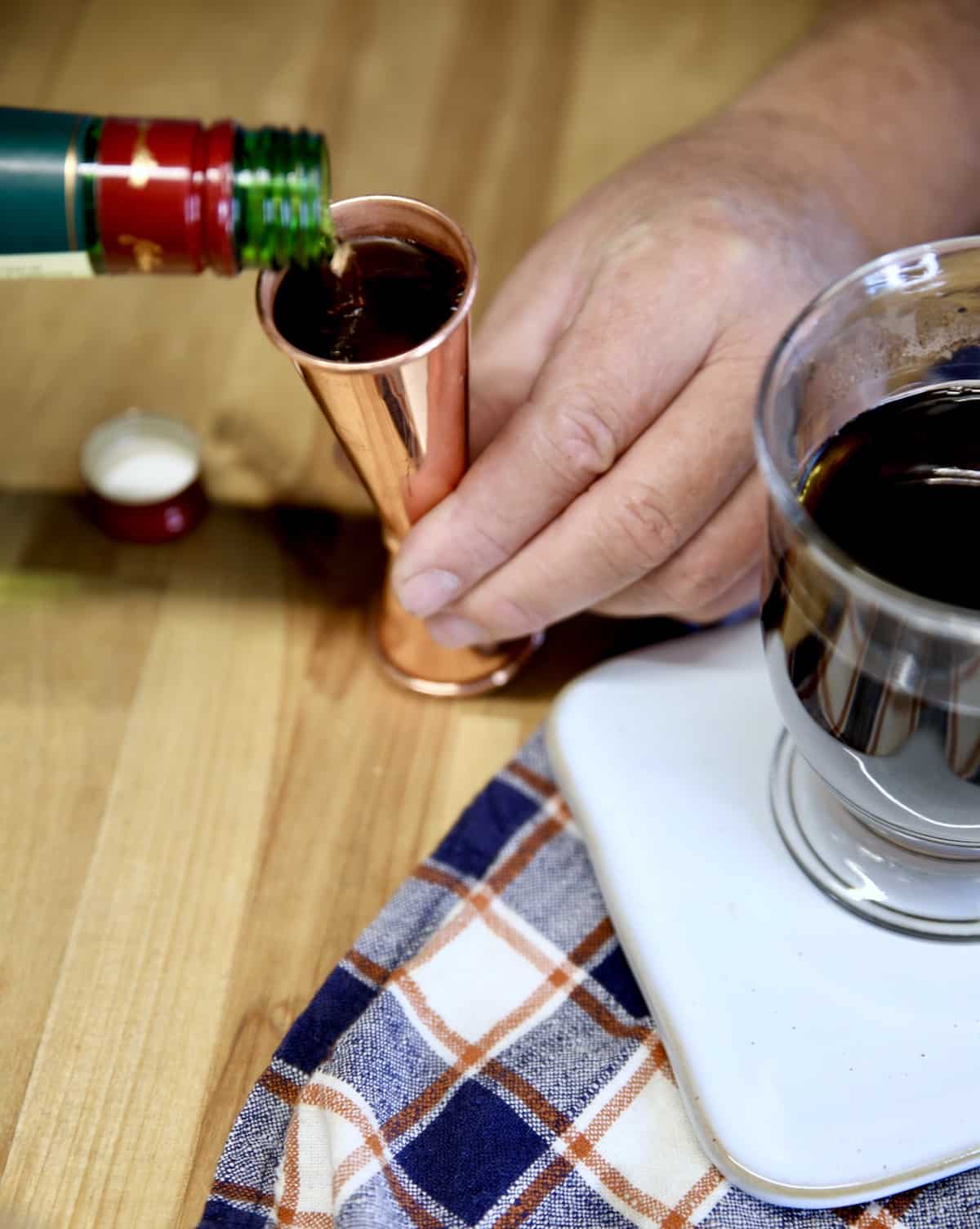 Pouring Irish whiskey into a copper jigger.