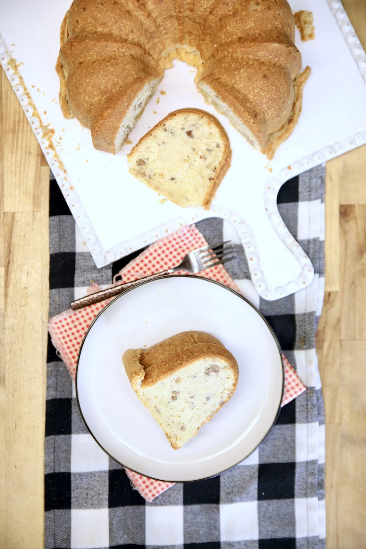 Overhead of bundt cake on a platter, slice on a plate.