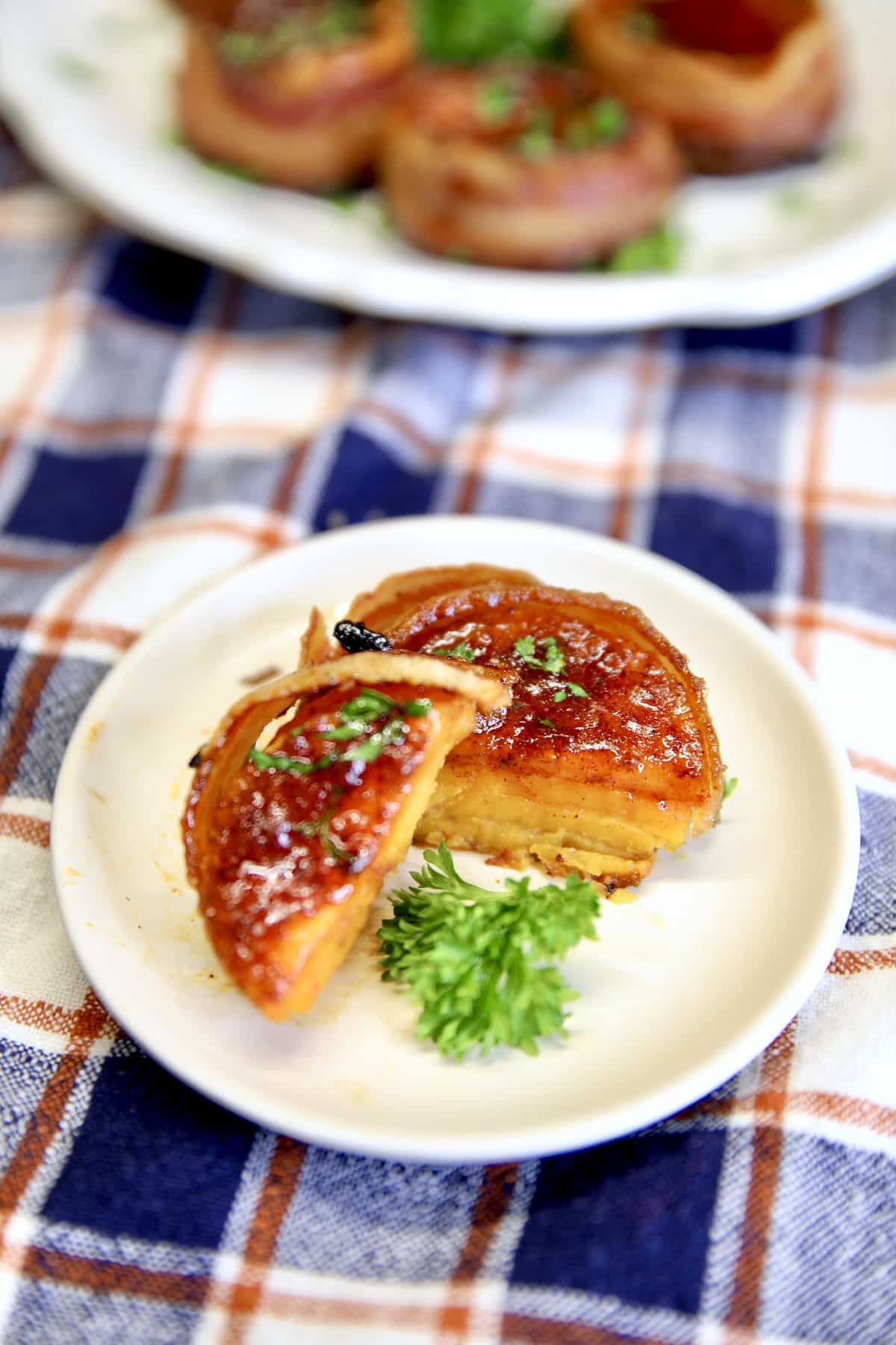Bacon wrapped sweet potato stack on a small plate, sliced in half.