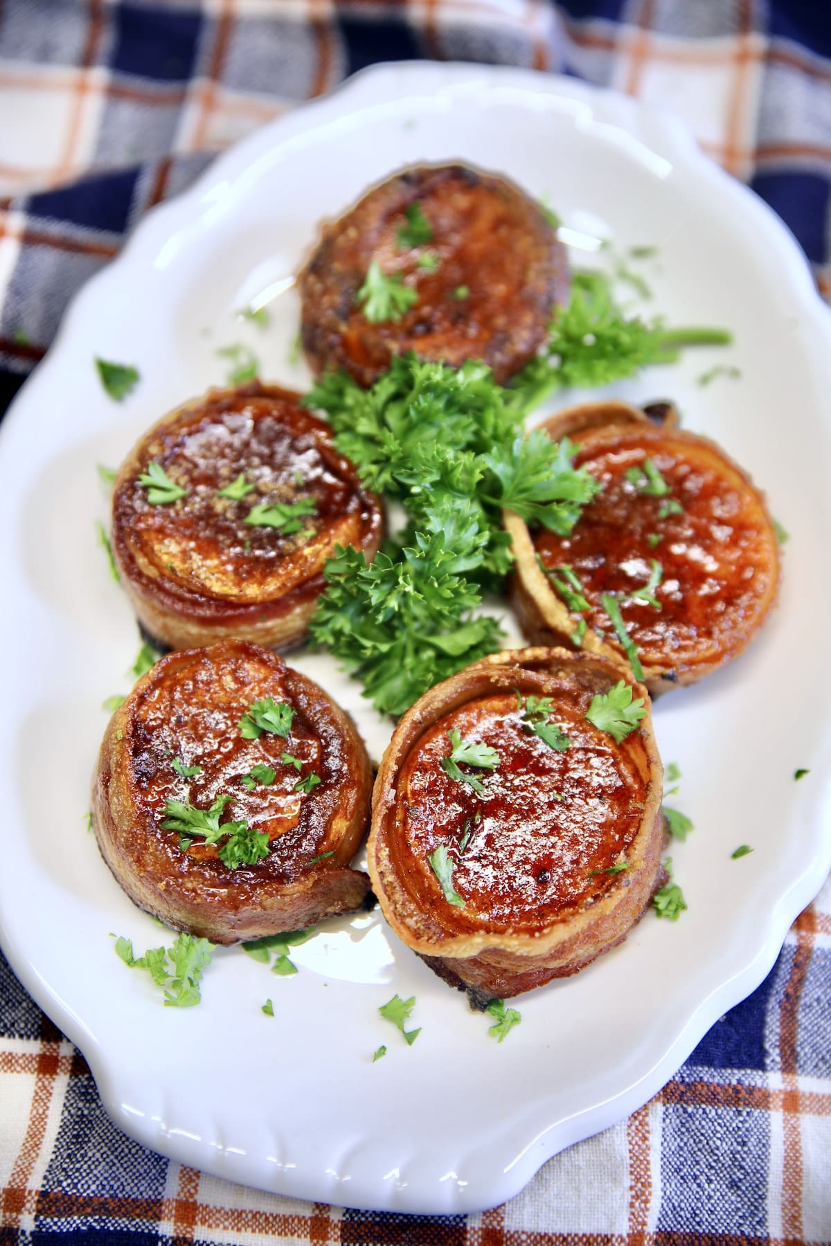 Bacon Wrapped Sweet Potatoes on a platter with parsley.