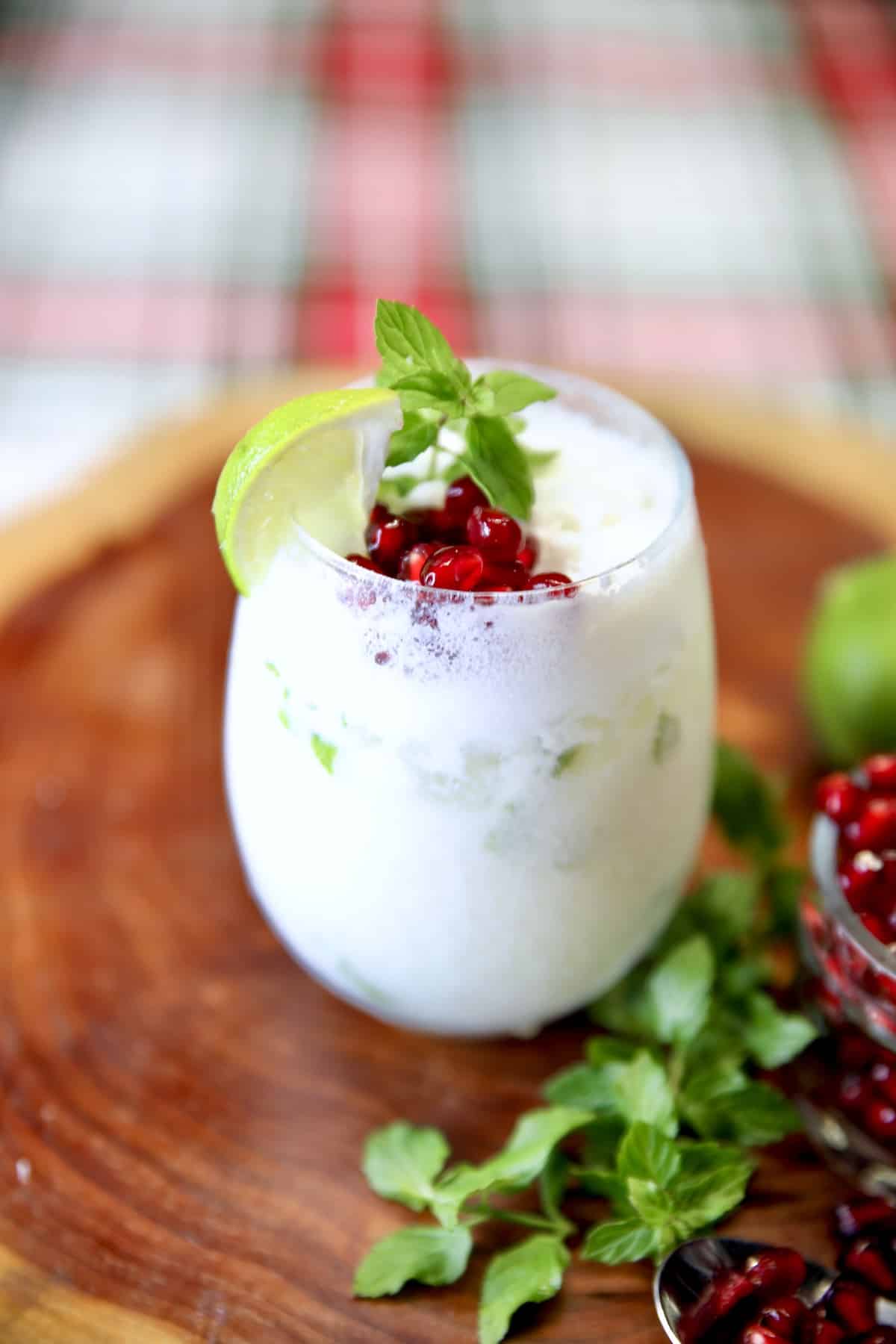 Coconut cocktail with lime, mint and pomegranate garnish.