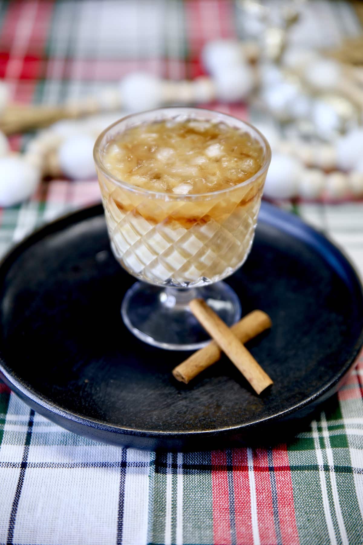 Eggnog White Russian cocktail with cinnamon sticks on a black plate.
