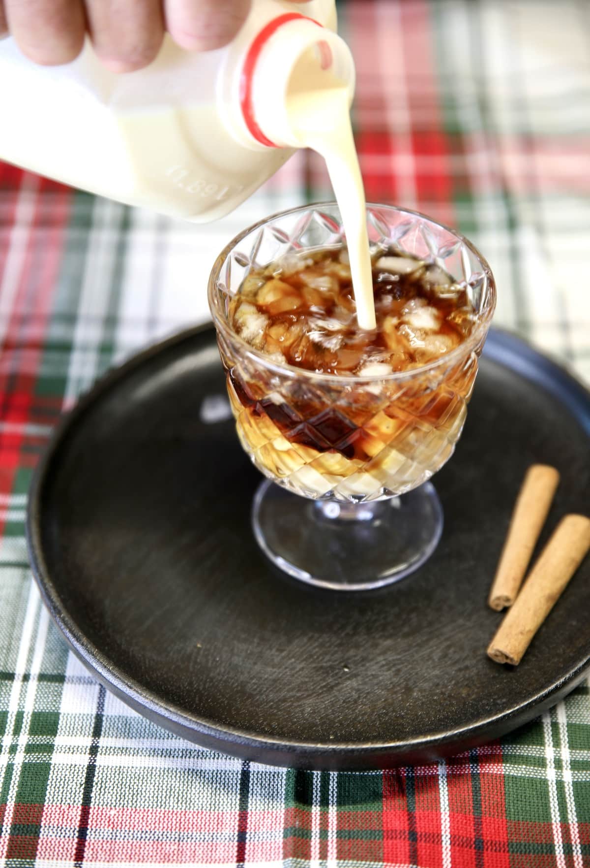 Pouring eggnog into a cocktail glass.