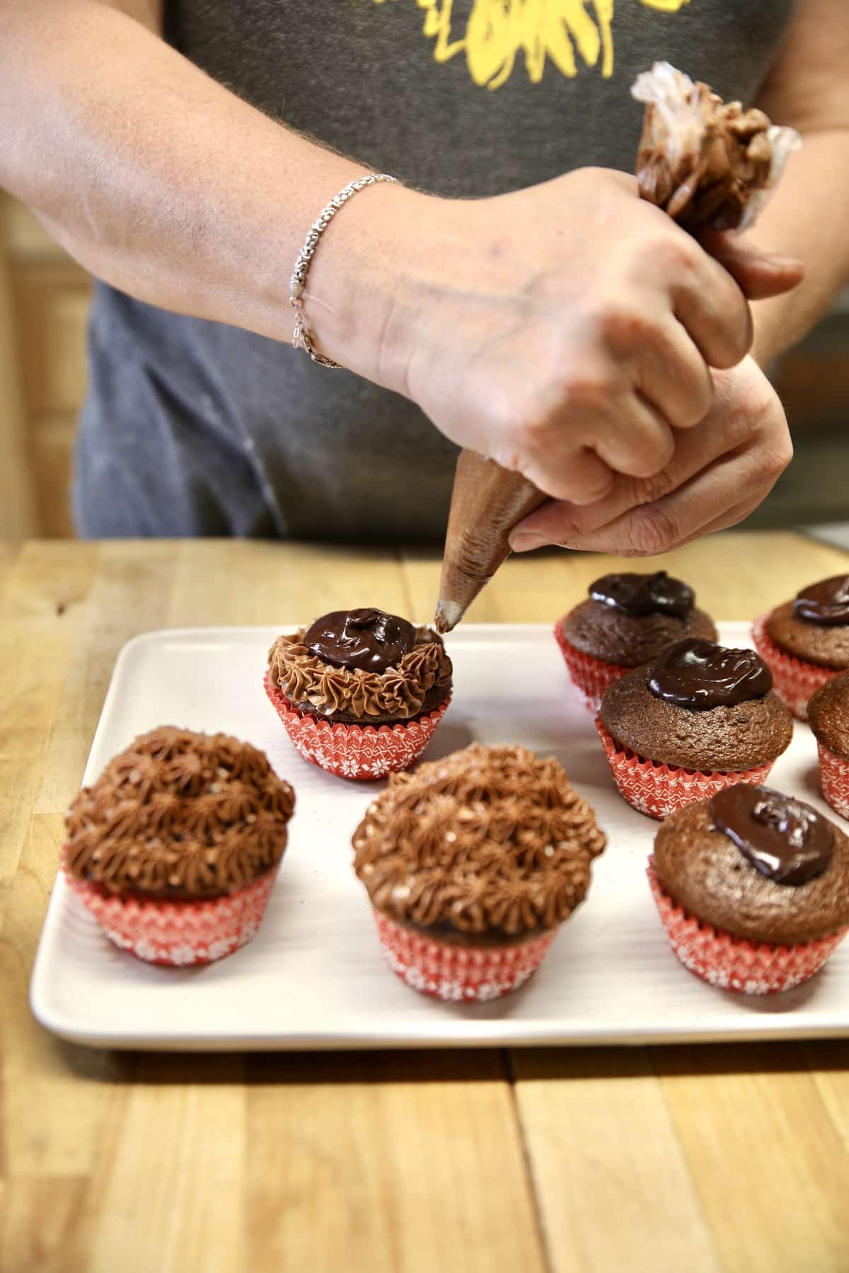 Frosting chocolate cupcakes with icing bag.