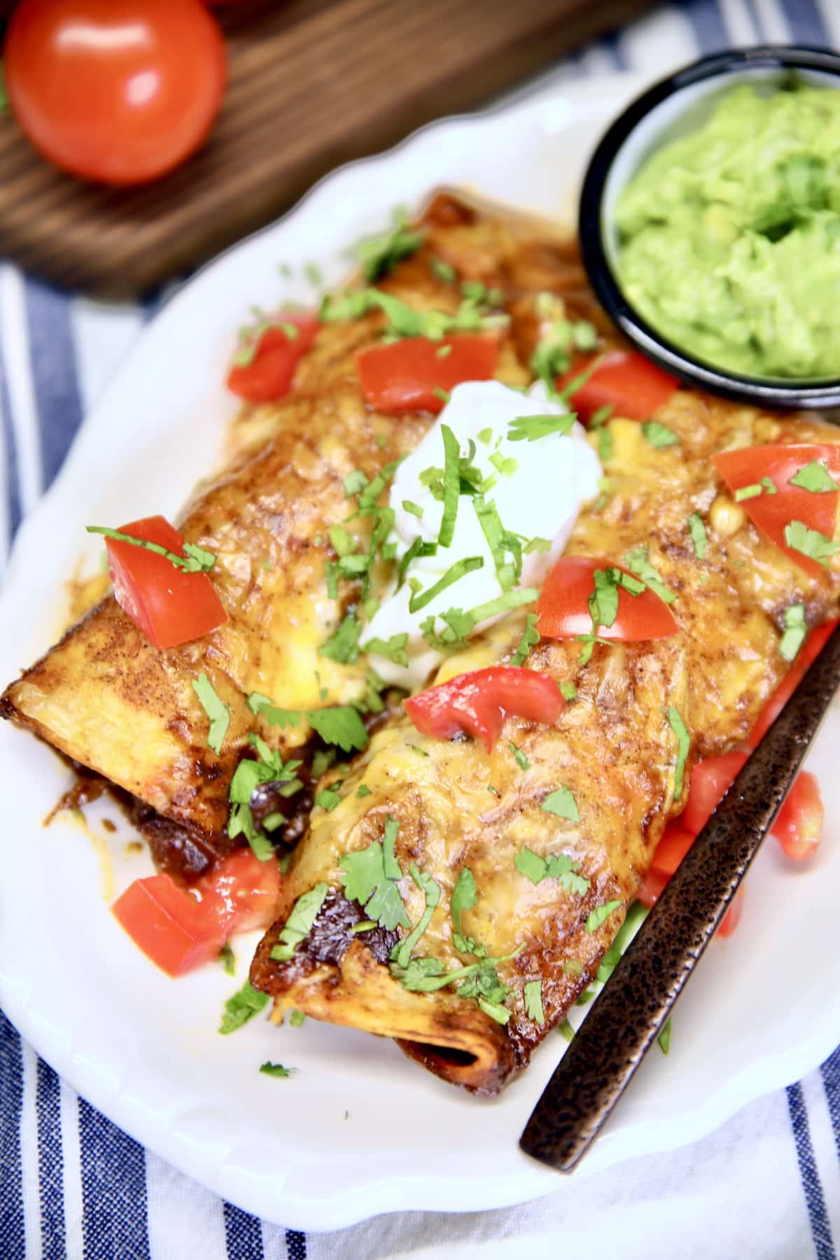 Overhead view of plate of enchiladas, bowl of guacamole.