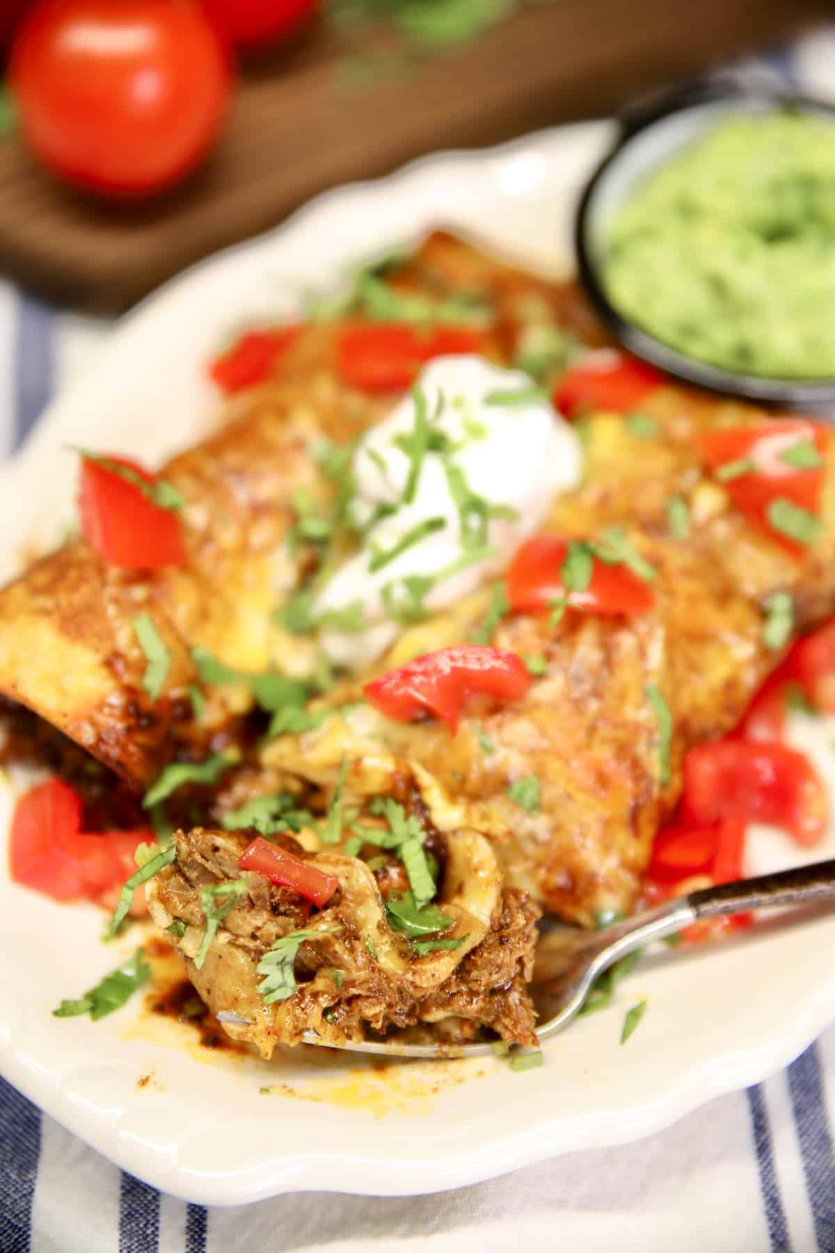 Brisket Enchiladas on a plate, bite on a fork.