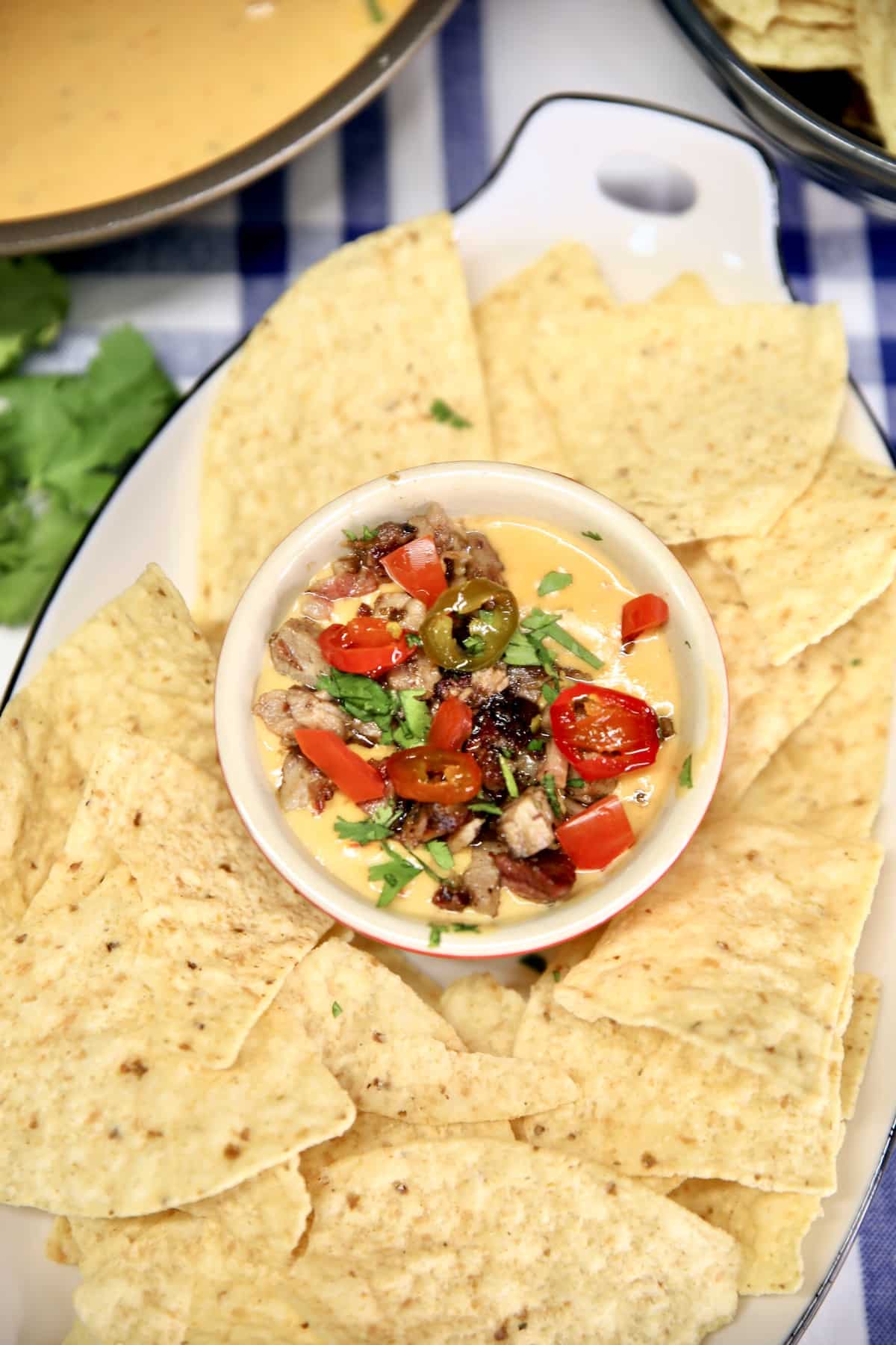 Bowl of brisket queso dip in a platter of tortilla chips.