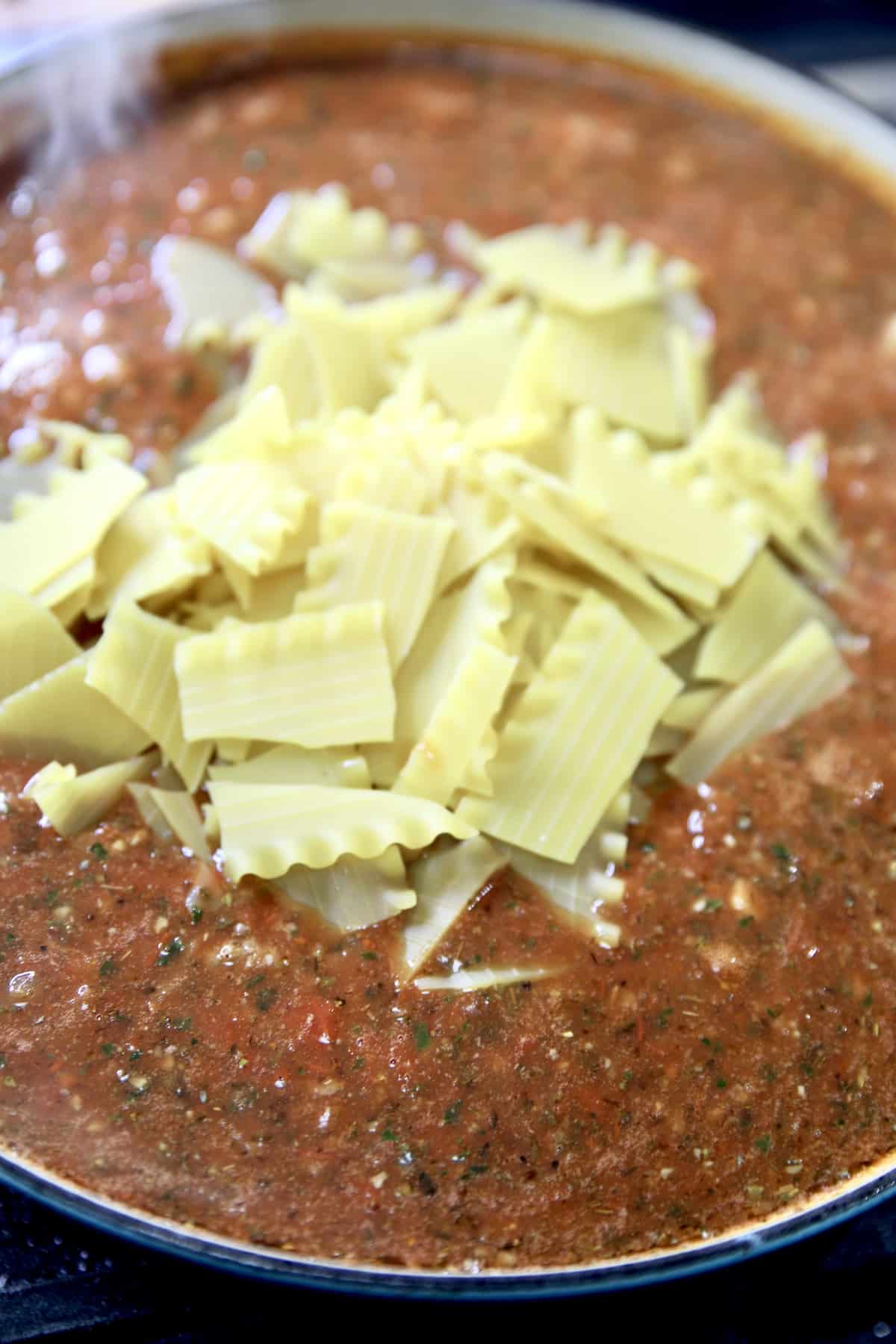 Adding broken lasagna noodles to soup.