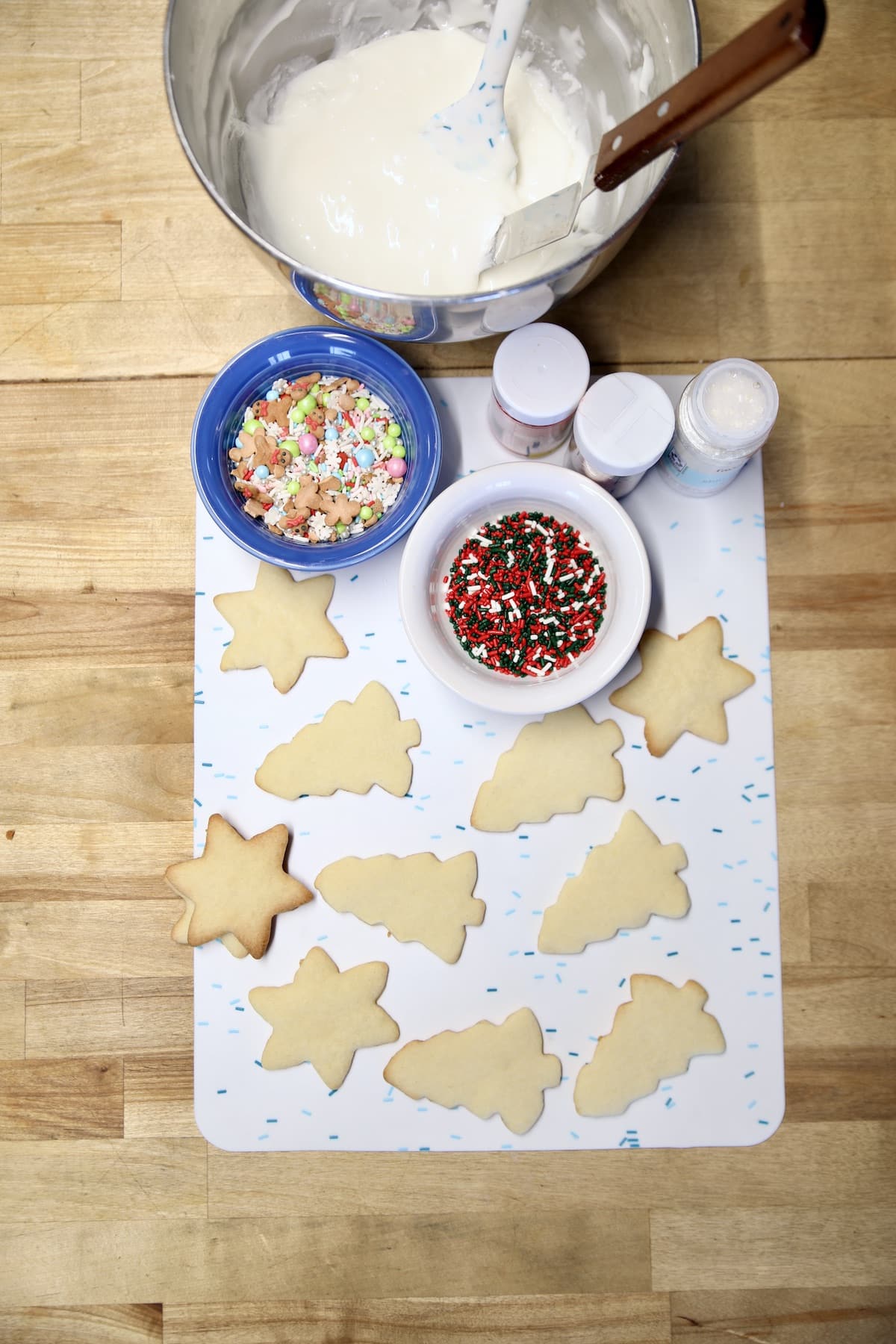 Bowl of icing, sprinkles, sugar cookies.