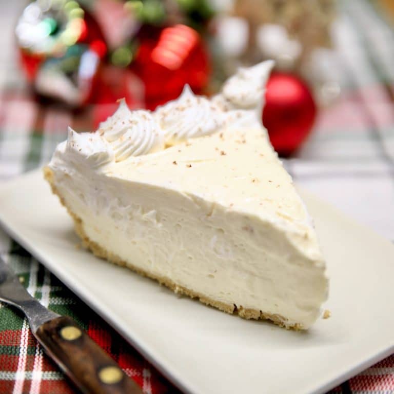 Slice of Eggnog Cheesecake, Christmas decor in background.