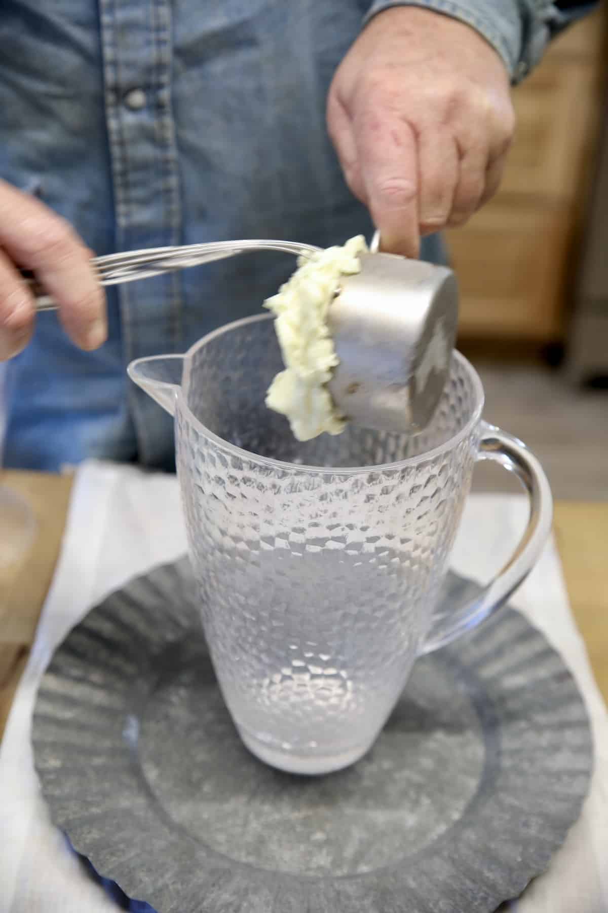 Adding sherbet to a pitcher for punch.