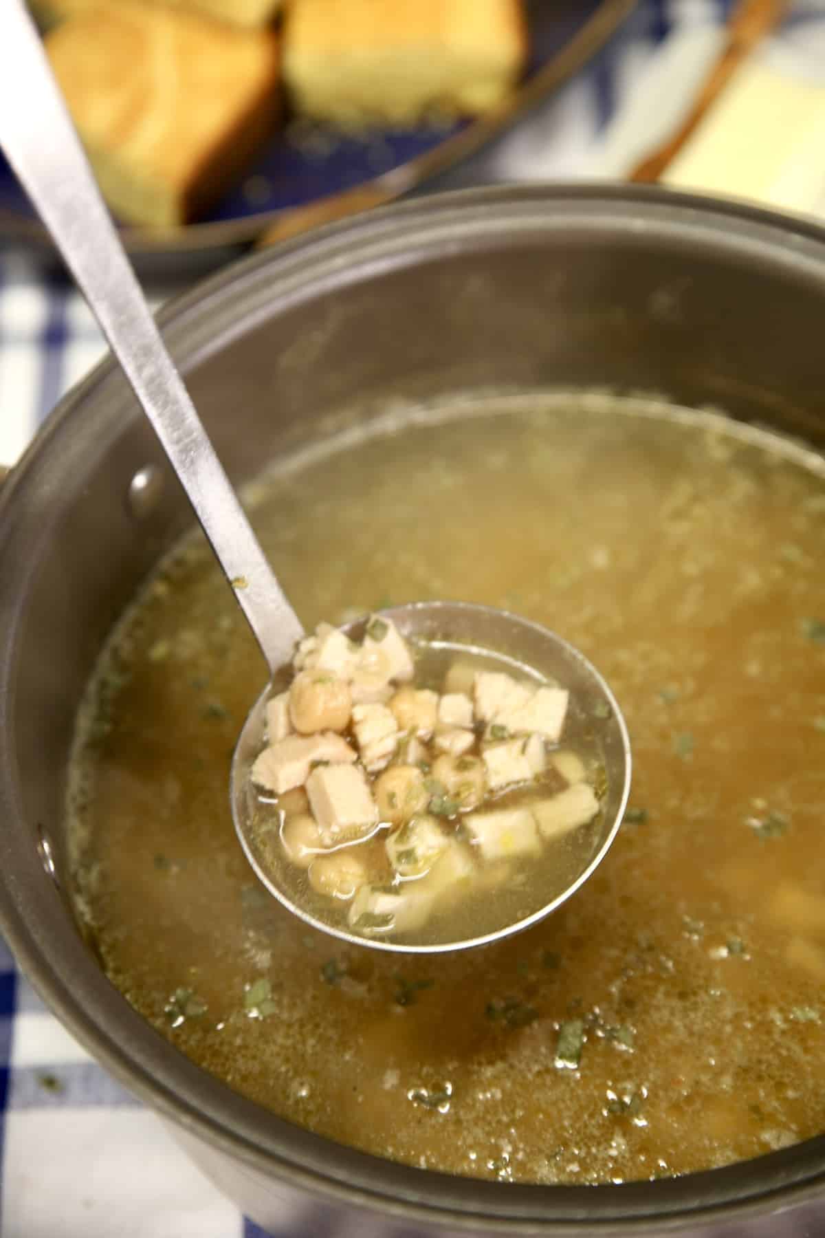 Ladle full of chickpea chicken soup from the pan.