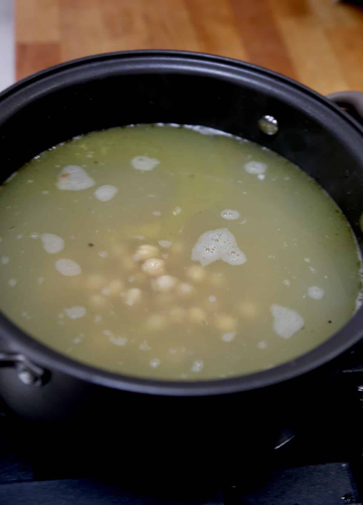 Chickpeas added to chicken soup pan.