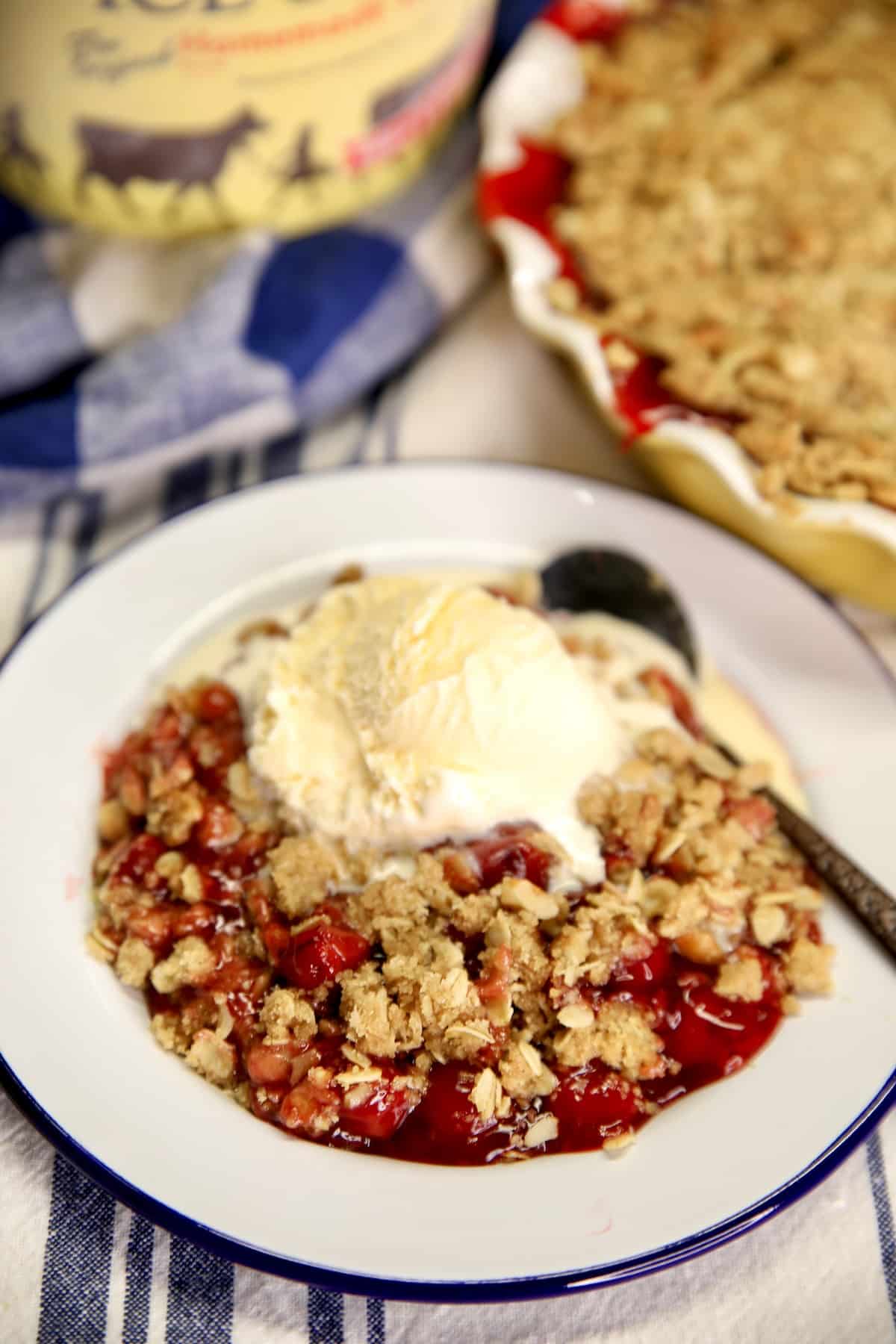 Plate of cherry crisp topped with vanilla ice cream.