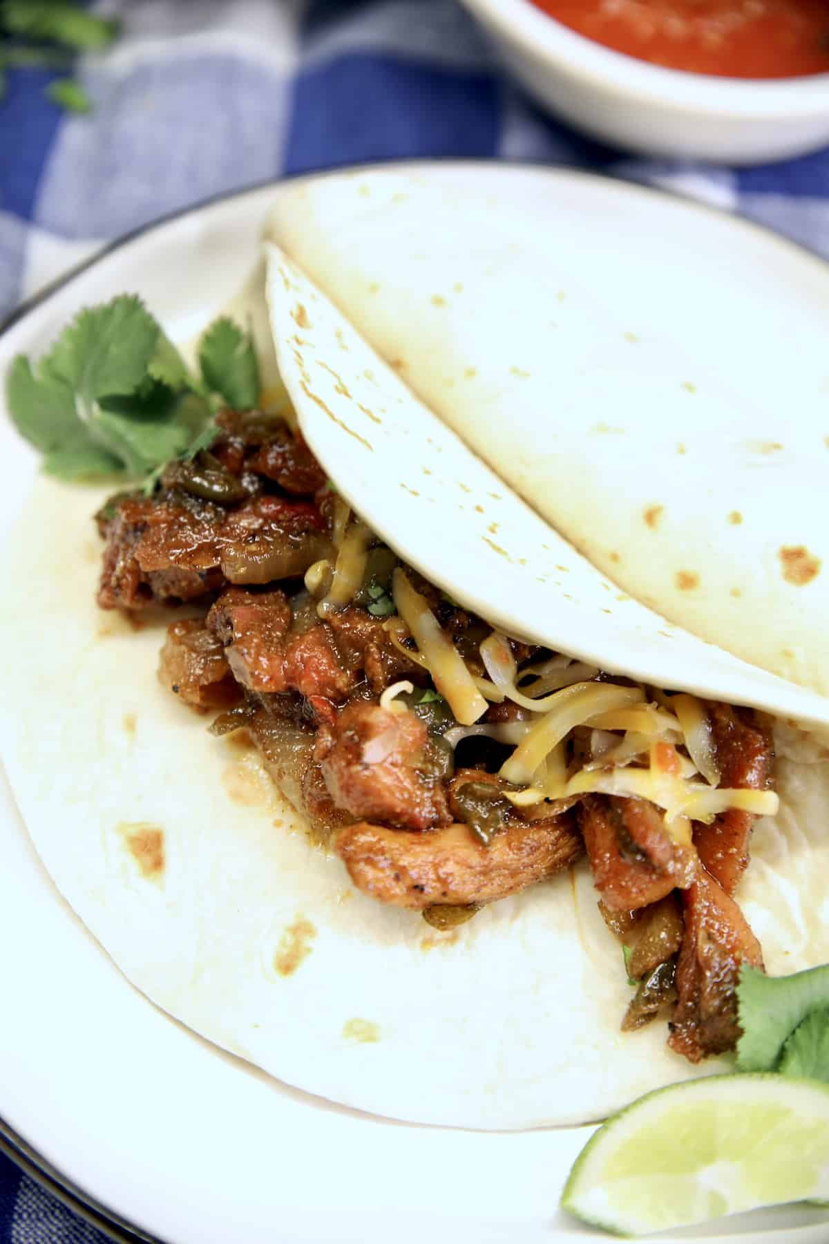 Plate of chicken fajitas with lime slice and cilantro.