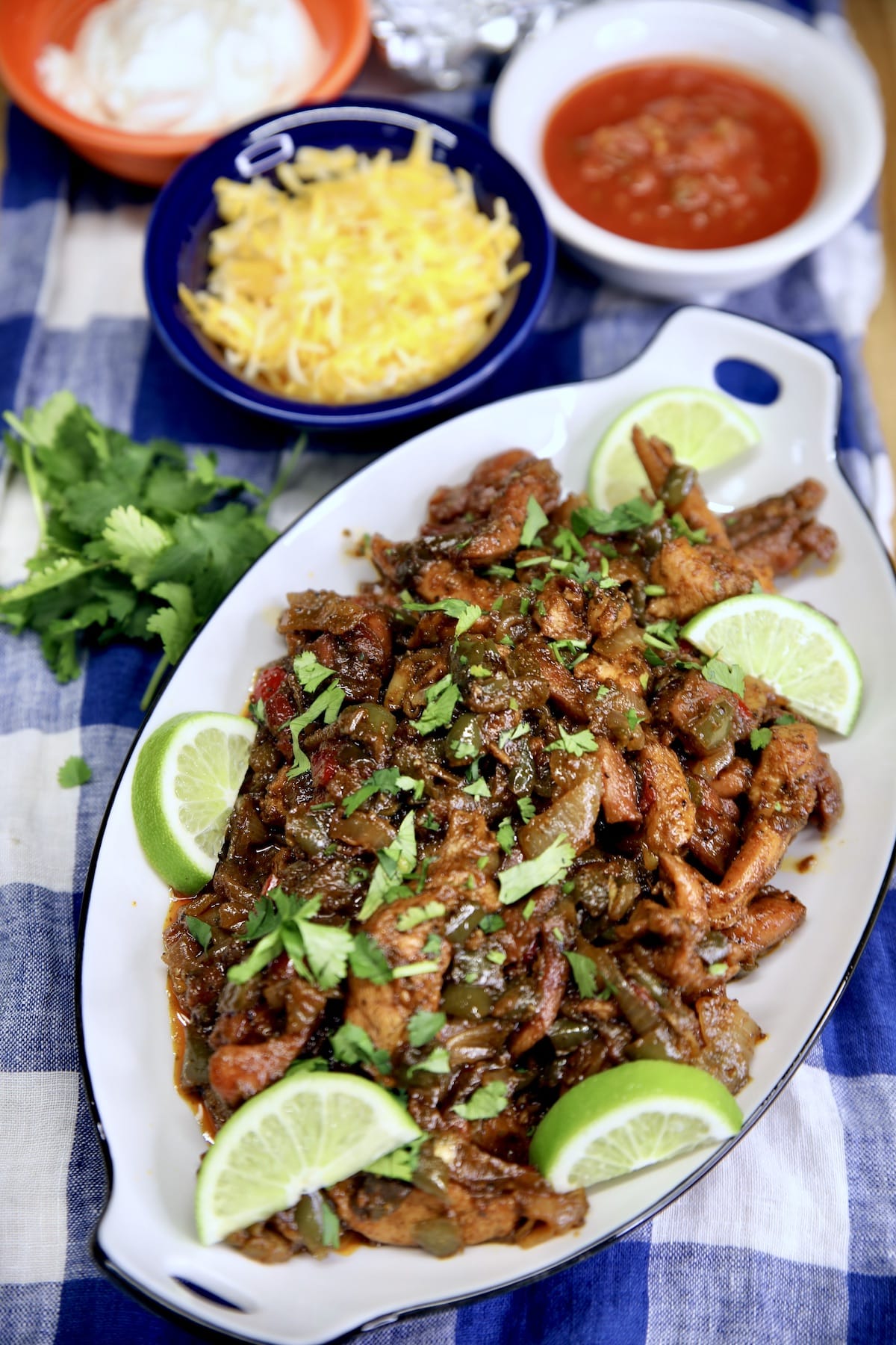 Platter of chicken fajitas, bowls of condiments.