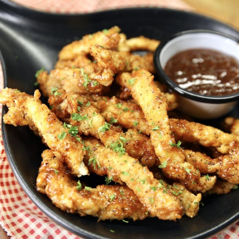 Chicken fries in a black dish with bbq sauce in a bowl.