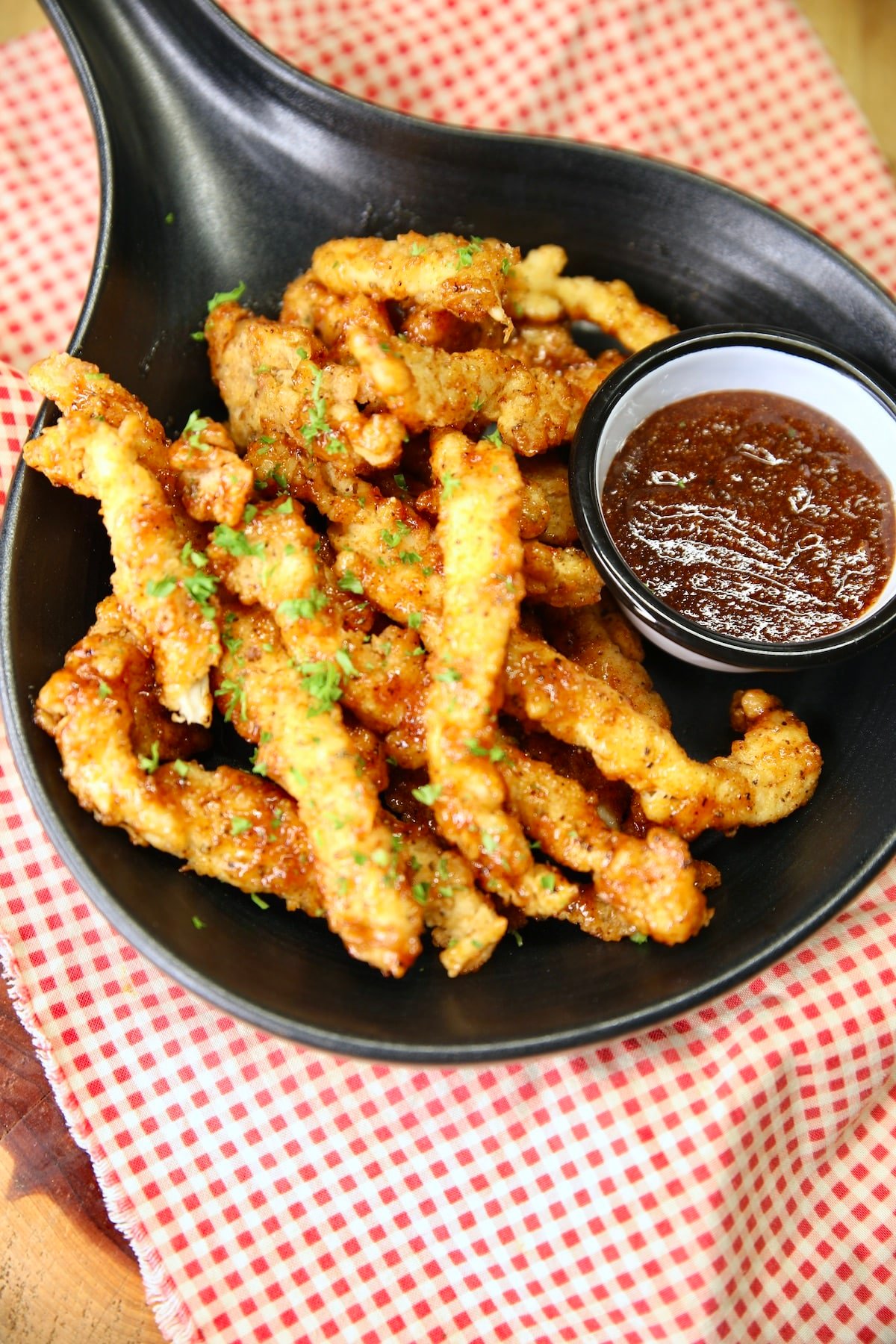Black dish with chicken fries and bbq sauce.