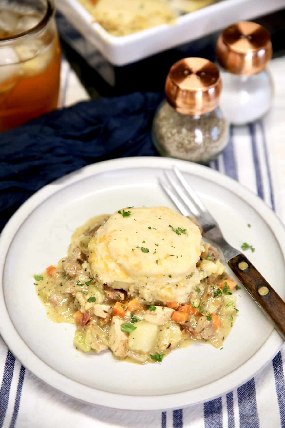 Plate of chicken and biscuits with pan in background.