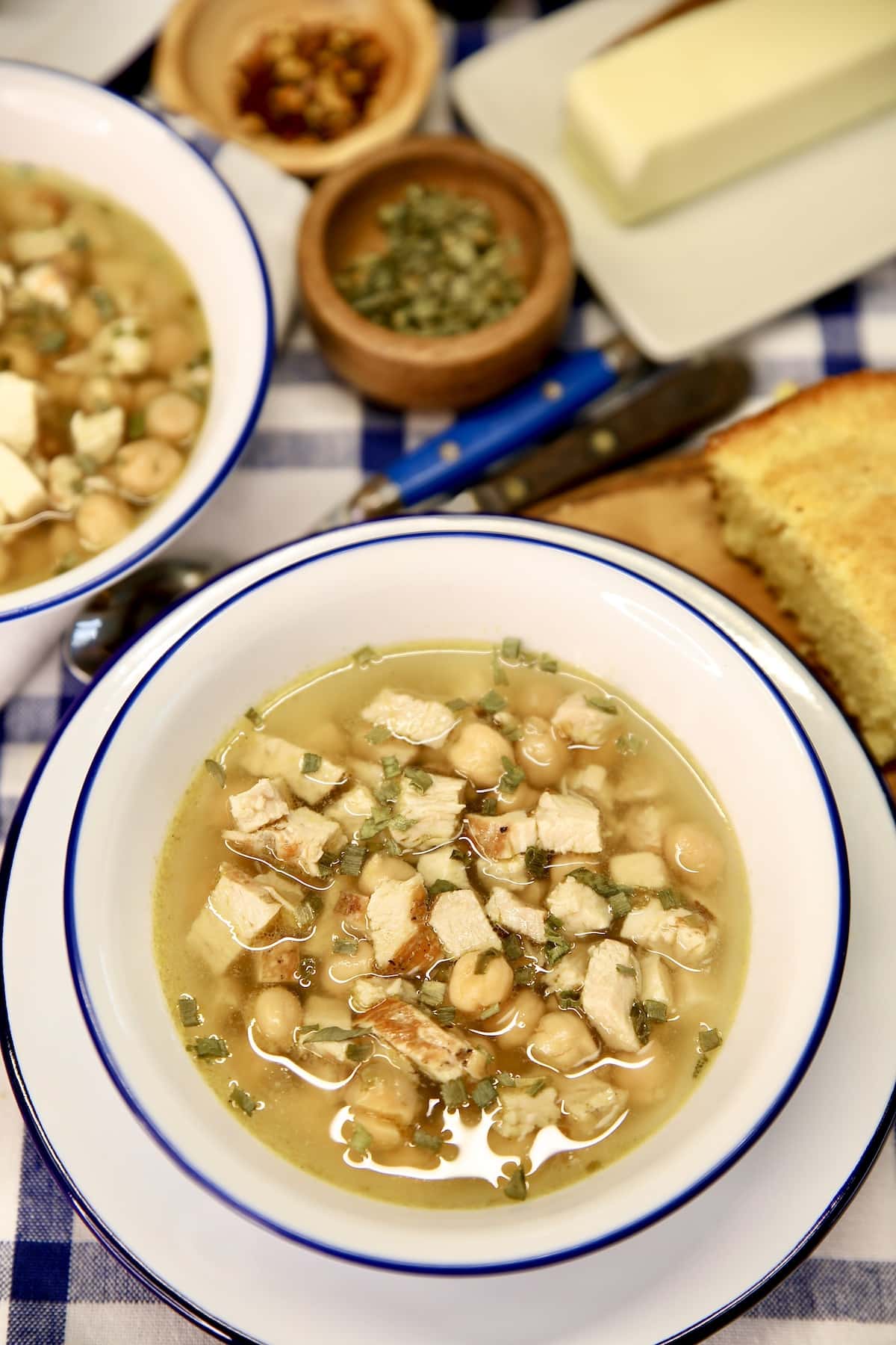 Bowls of chickpea chicken soup, herb bowls, butter.