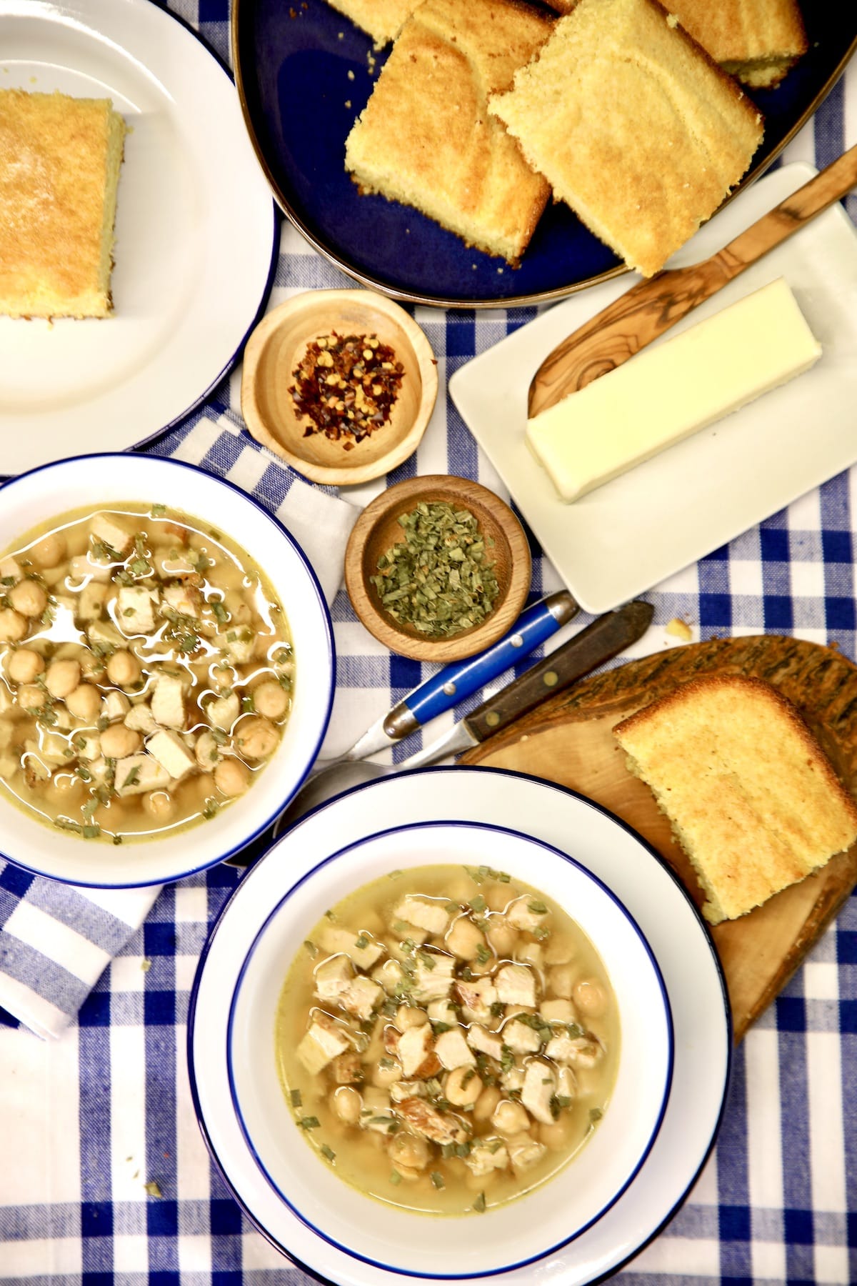 2 bowls of chickpea chicken soup, cornbread, butter, spices.